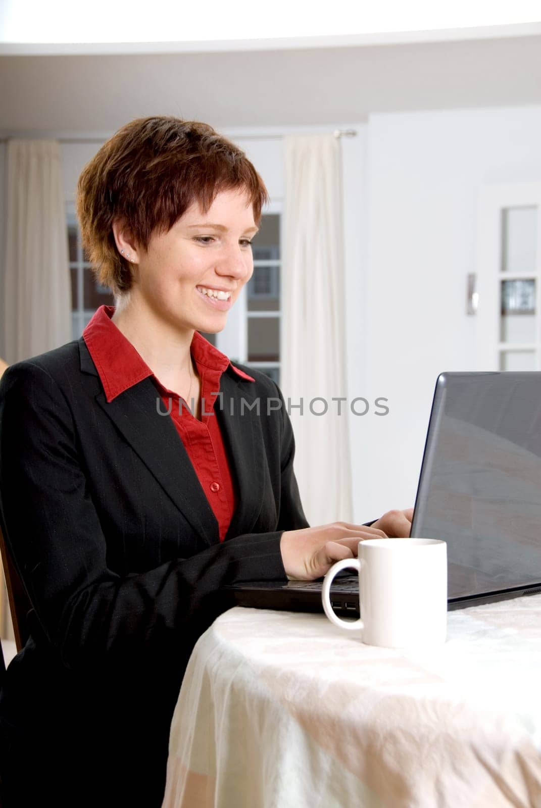 woman in a black suit working on her laptop