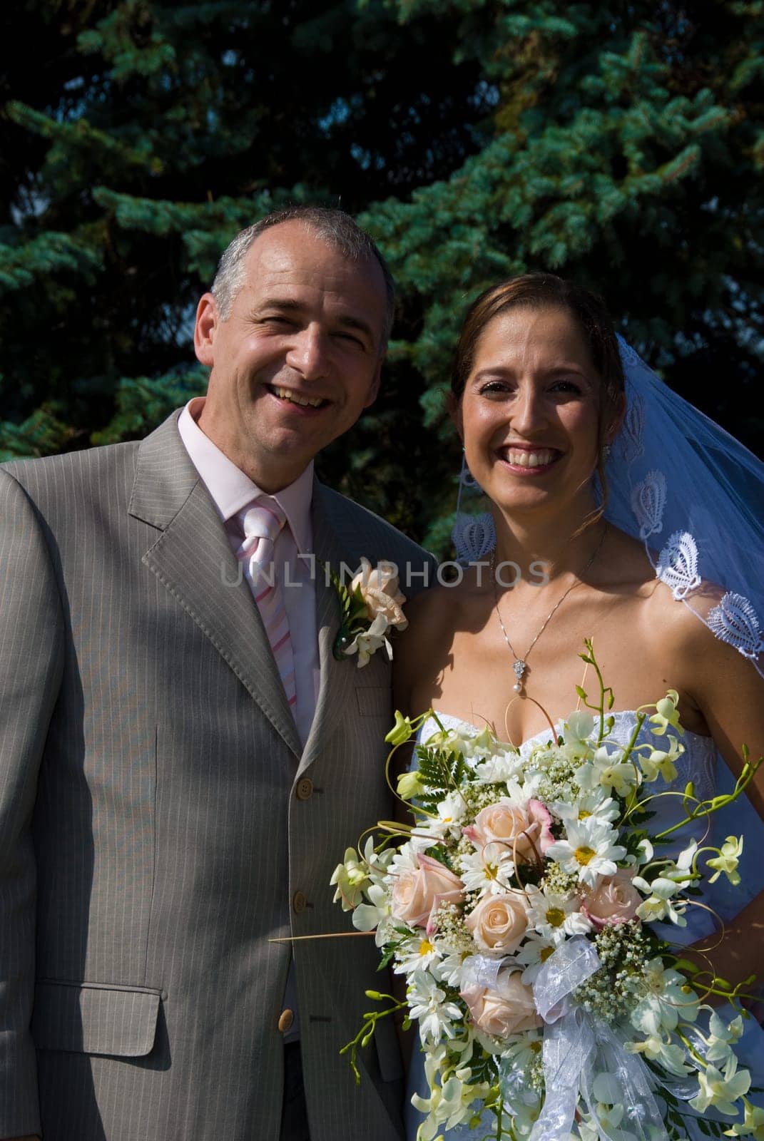 a bride and a groom posing behind some trees