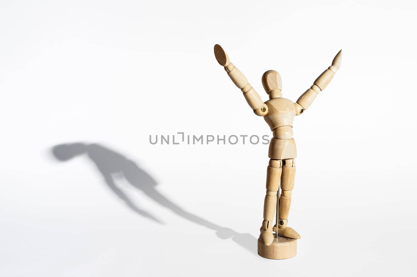 Happy wooden mannequin with sad shadow isolated in white background.