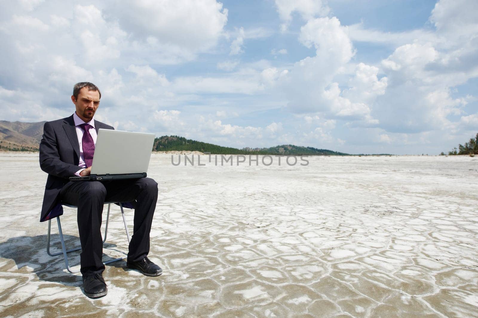 Photo of modern businessman typing on laptop outside with cloudy sky above
