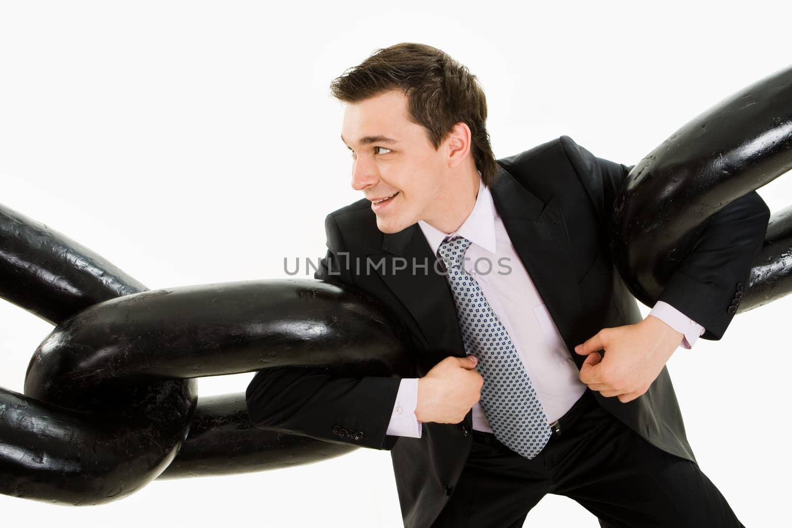 Portrait of powerful businessman holding two sections of huge chain by arms over white background