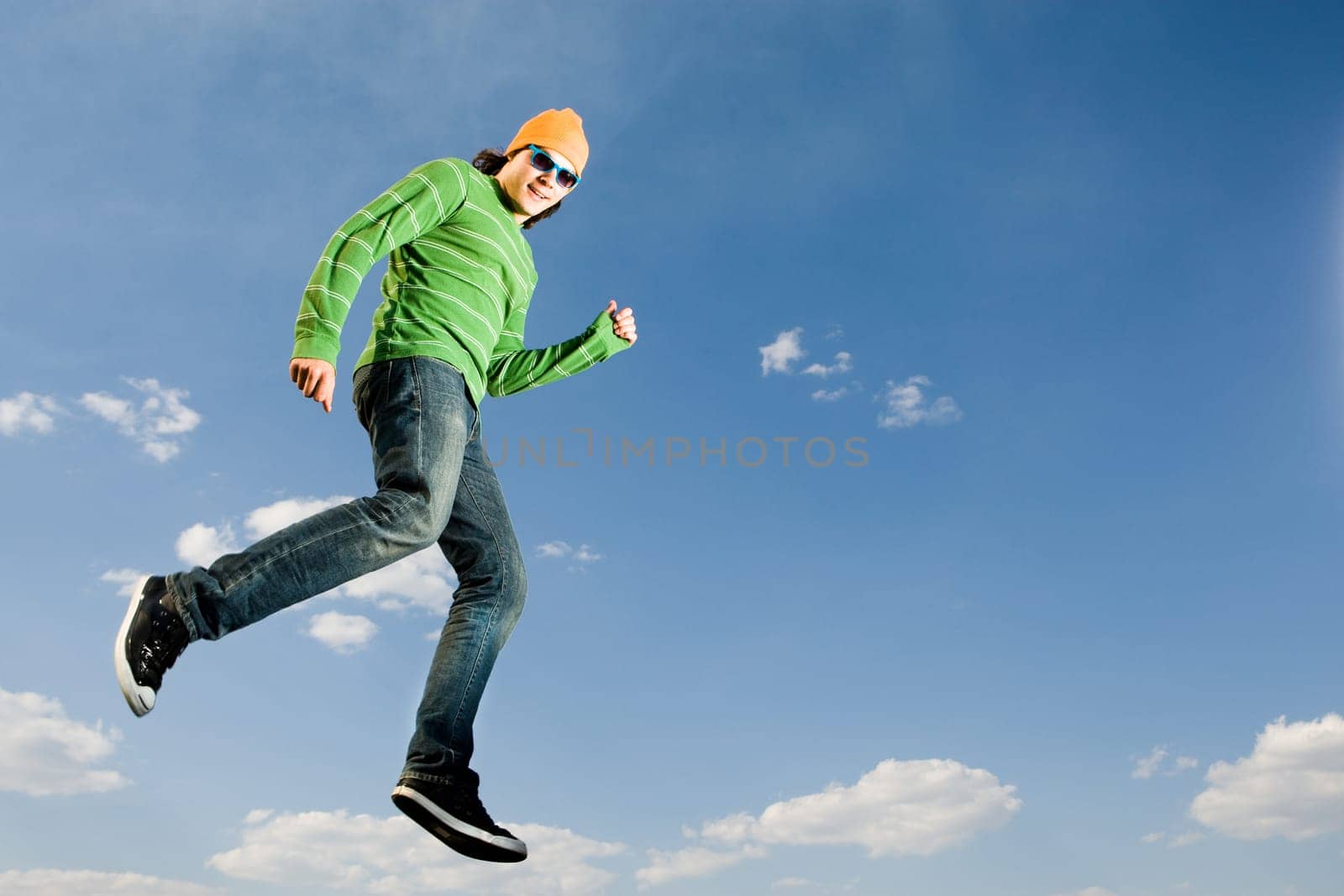 Image of cheerful man in high jump against bright blue sky