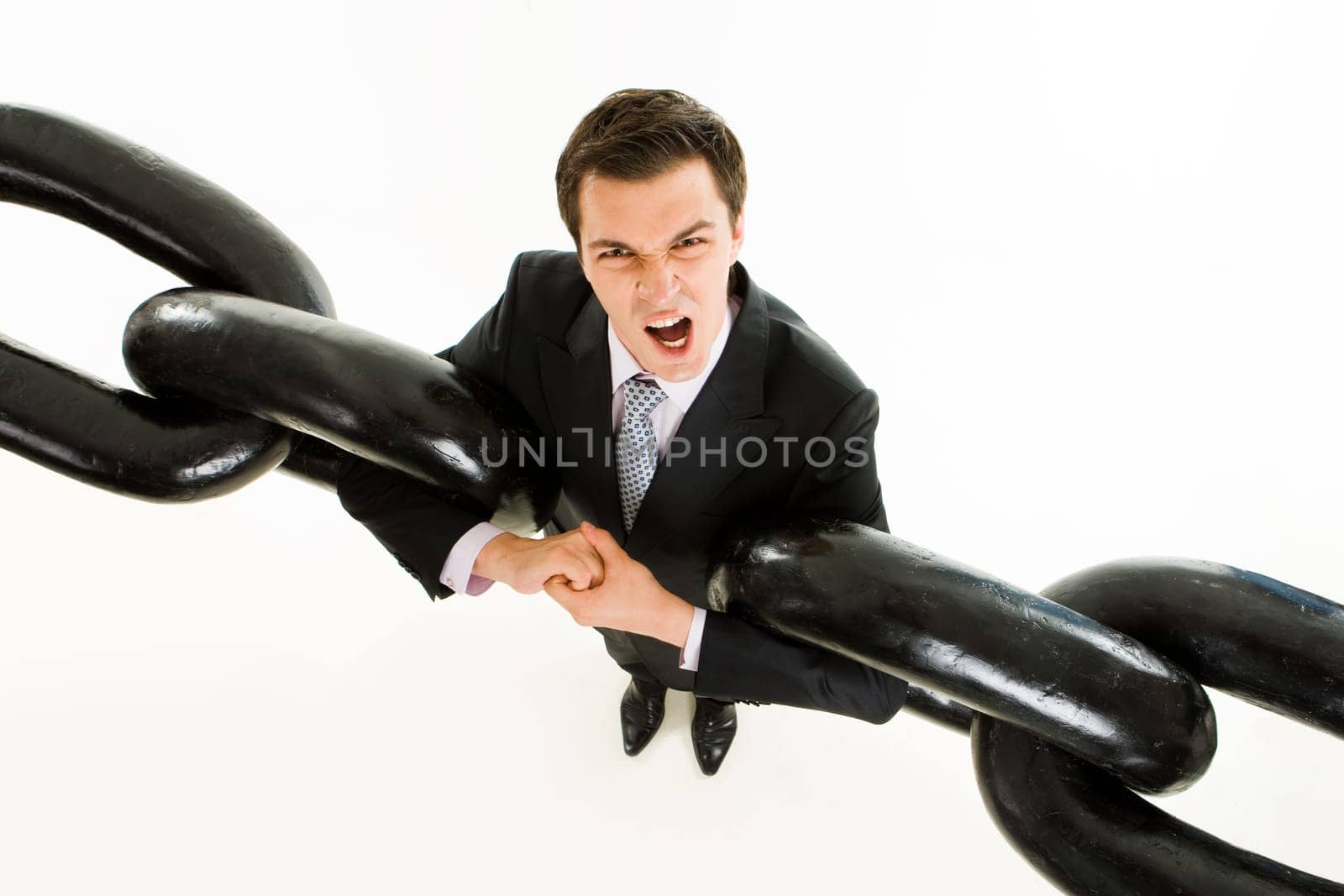 Portrait of tense businessman with two sections of heavy chain screaming into camera