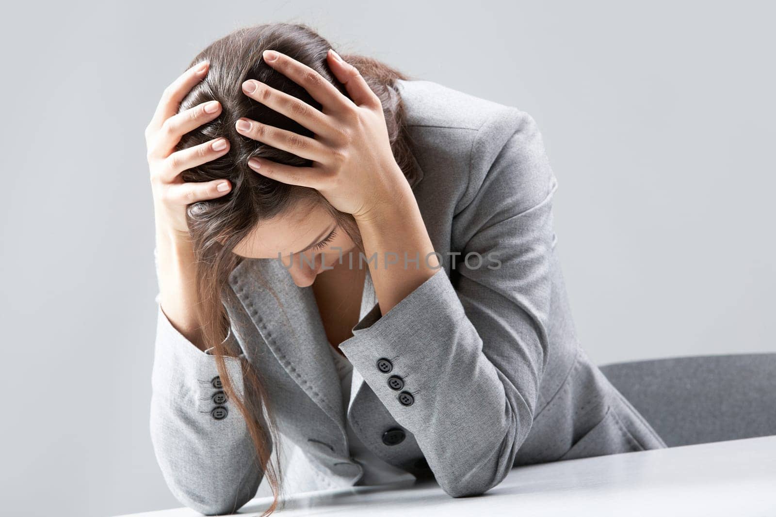 A businesswoman sitting at table and holding head in hands