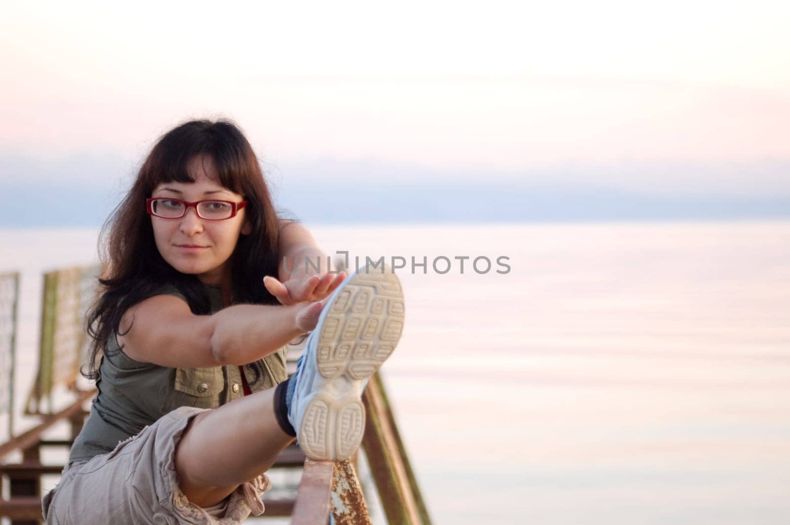 Portrait of young woman doing physical exercises outside by the river