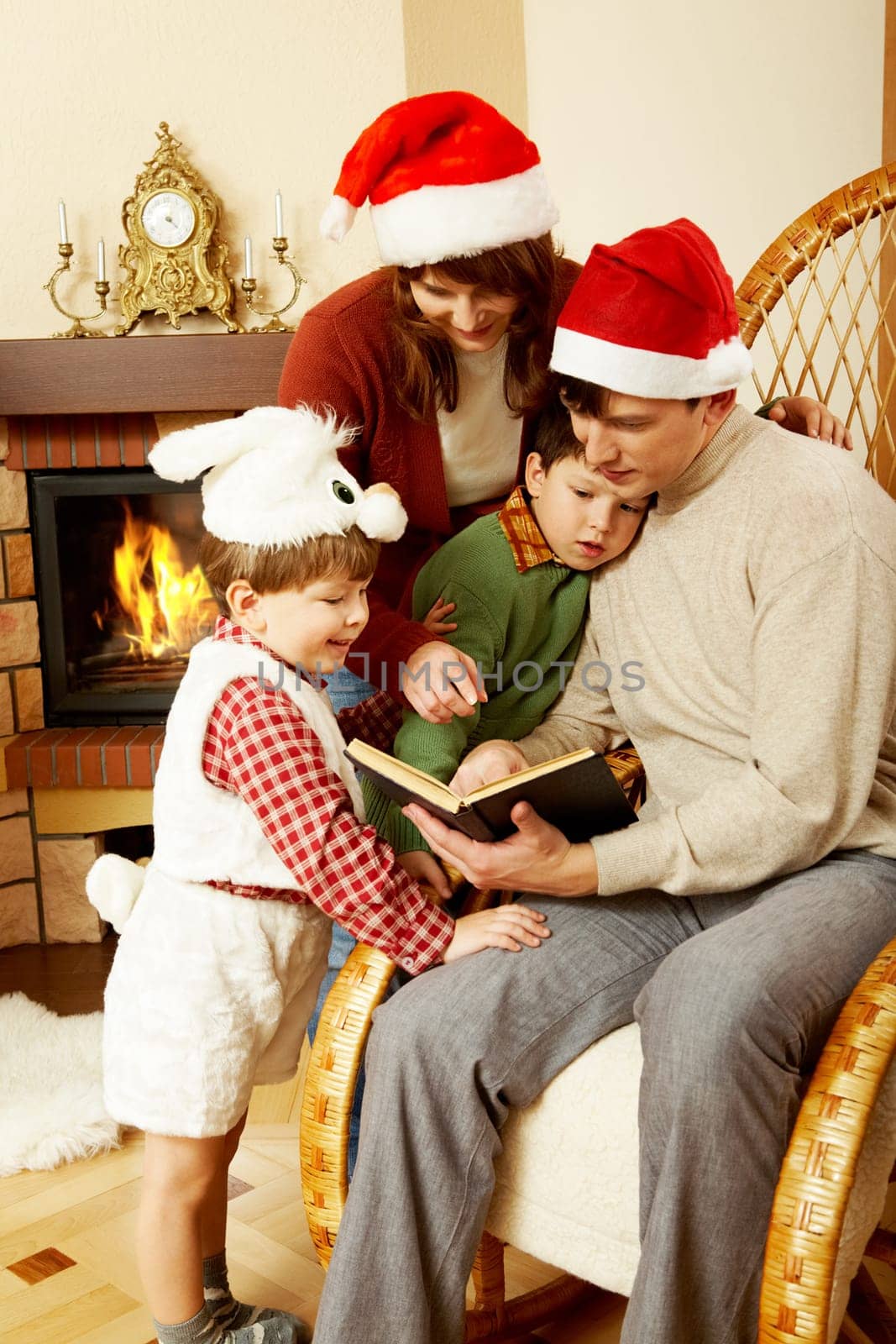 Portrait of family gathered together to read interesting fairy tale with fireplace behind