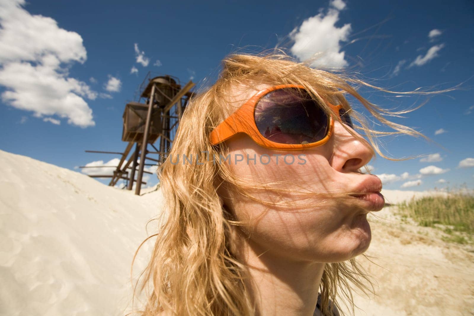 Portrait of young female in sunglasses protruding her lips on background of beach