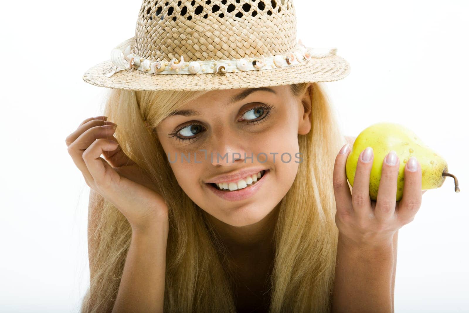 Smiling young sensual blond girl in summer hat is holding a pear
