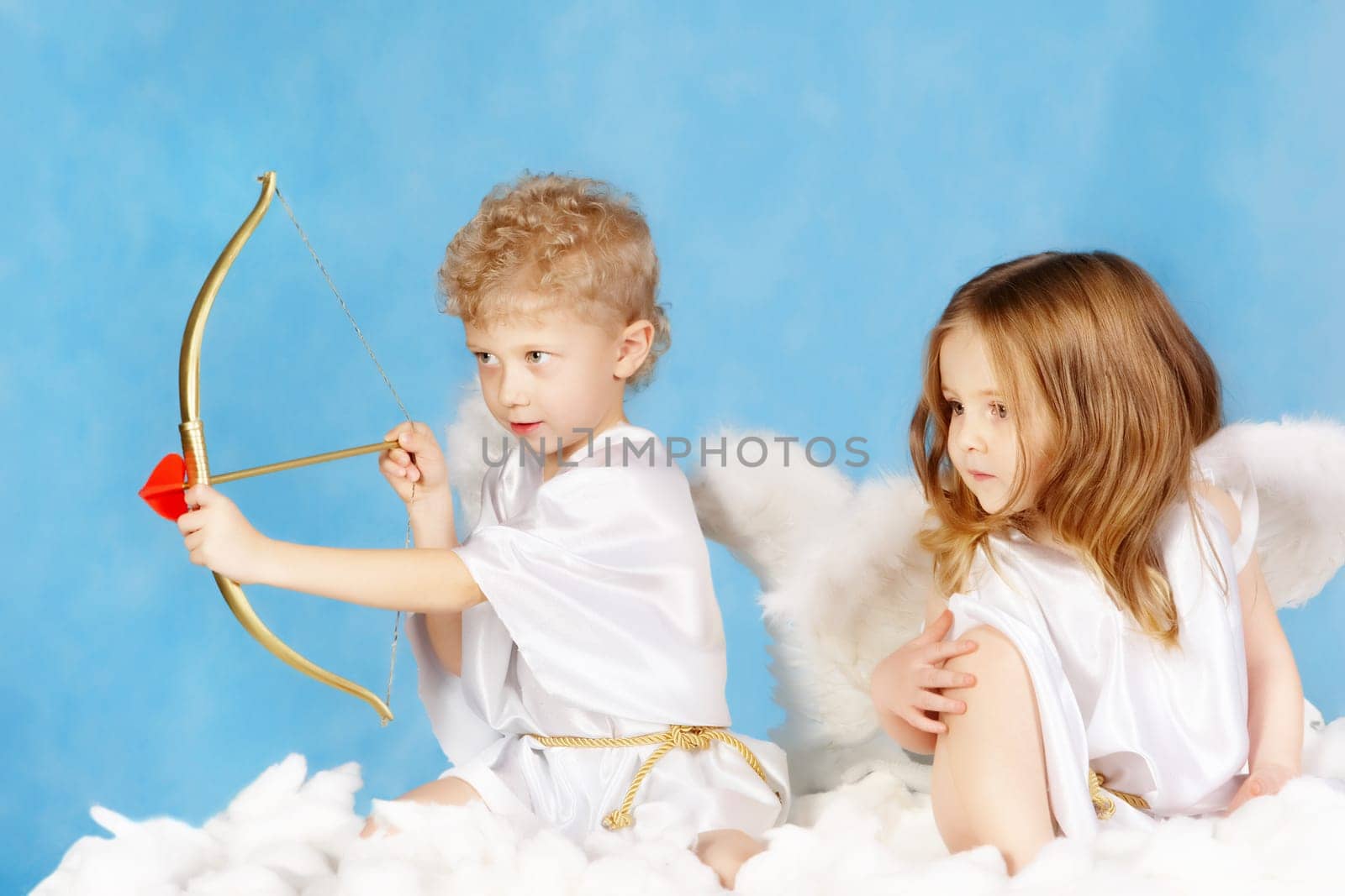 Portrait of two cute cupids sitting on the cloud