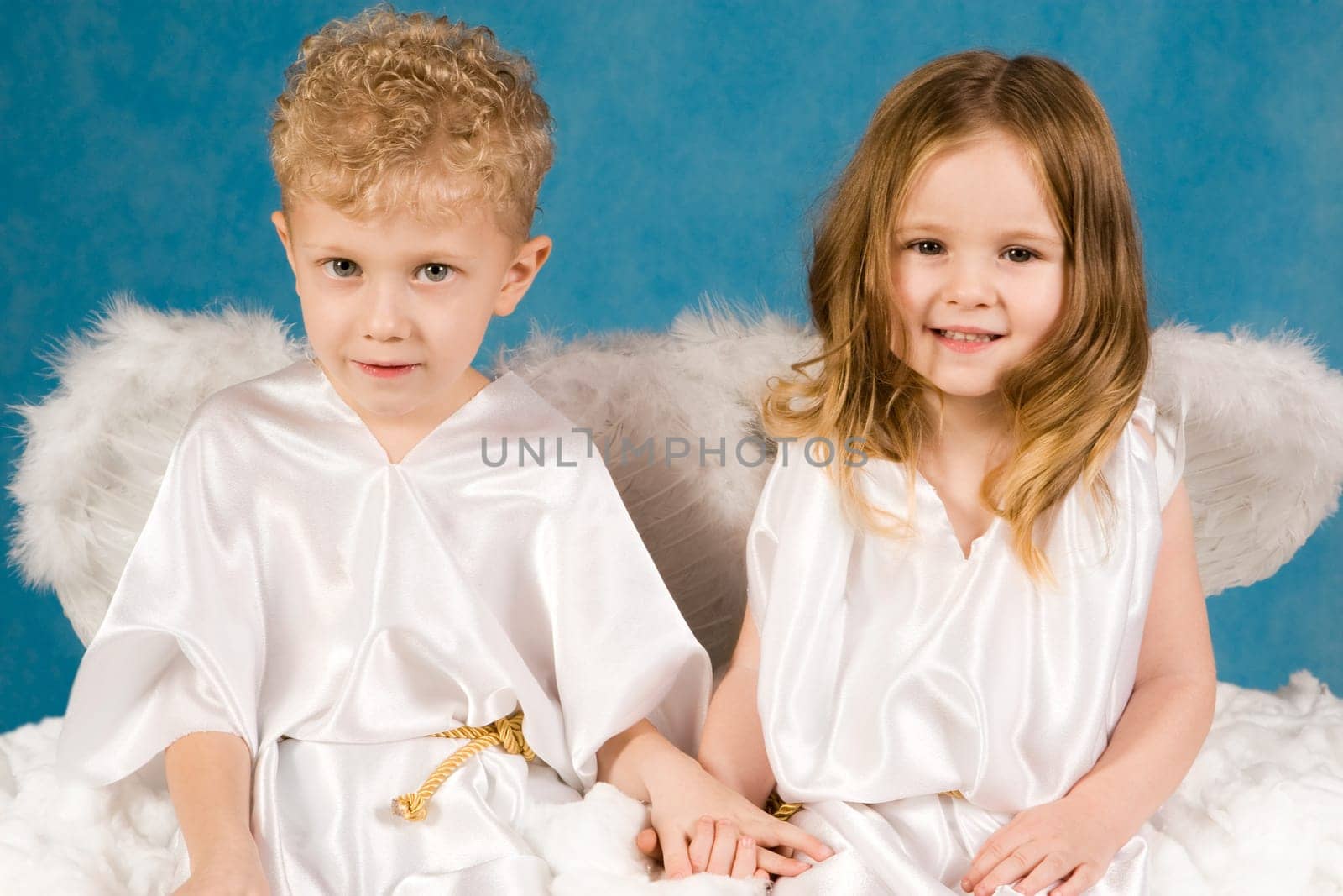 Portrait of two cute children wearing white silk clothing and looking at camera
