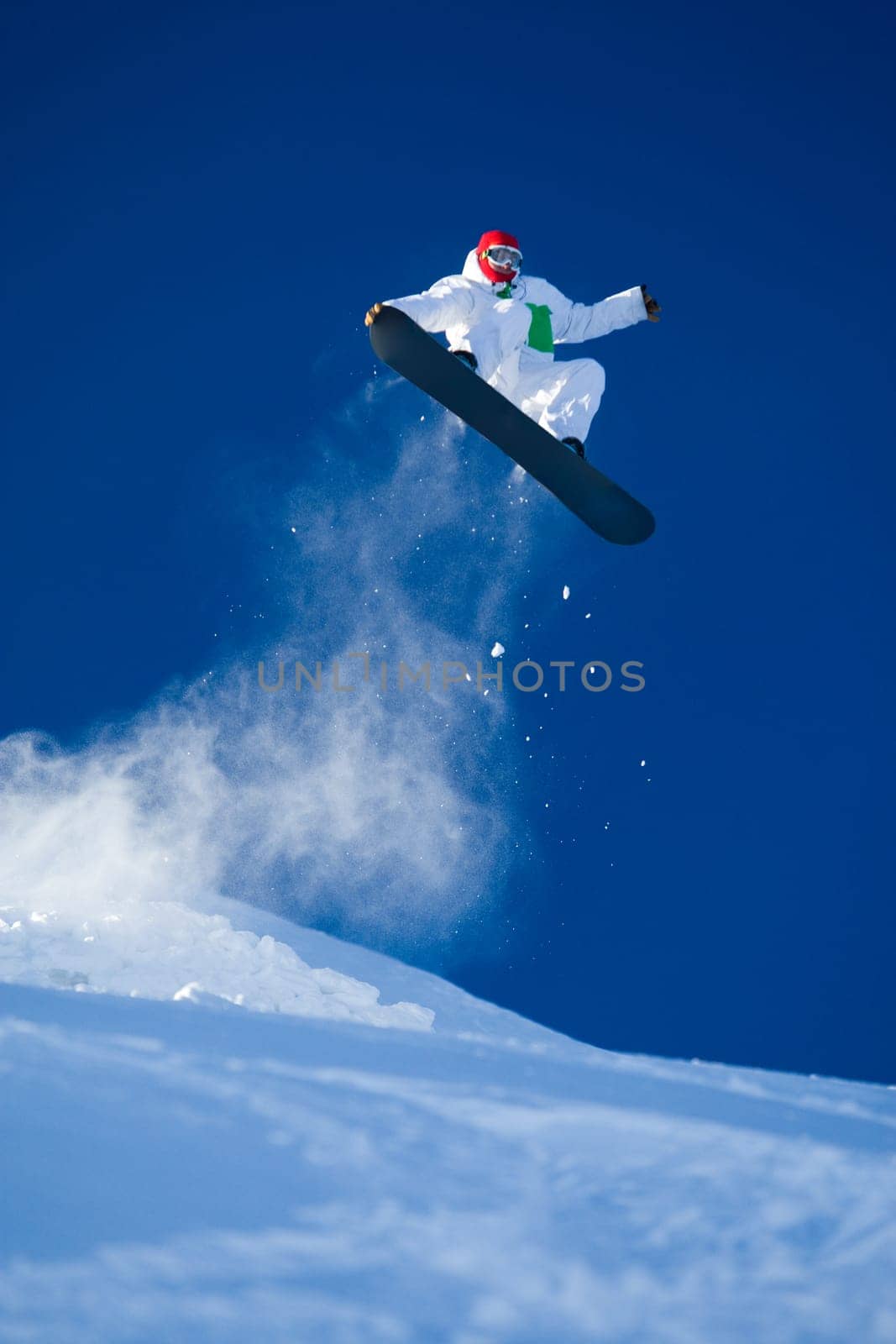Photo of brave sportsman jumping on snowboard over blue sky