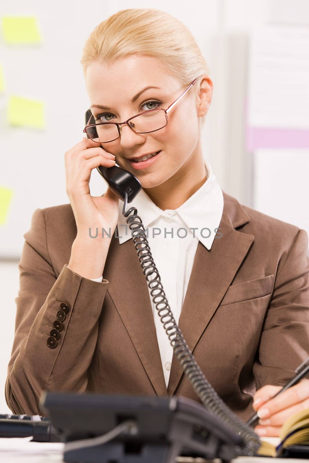 Portrait of helpful secretary speaking on the phone with a client