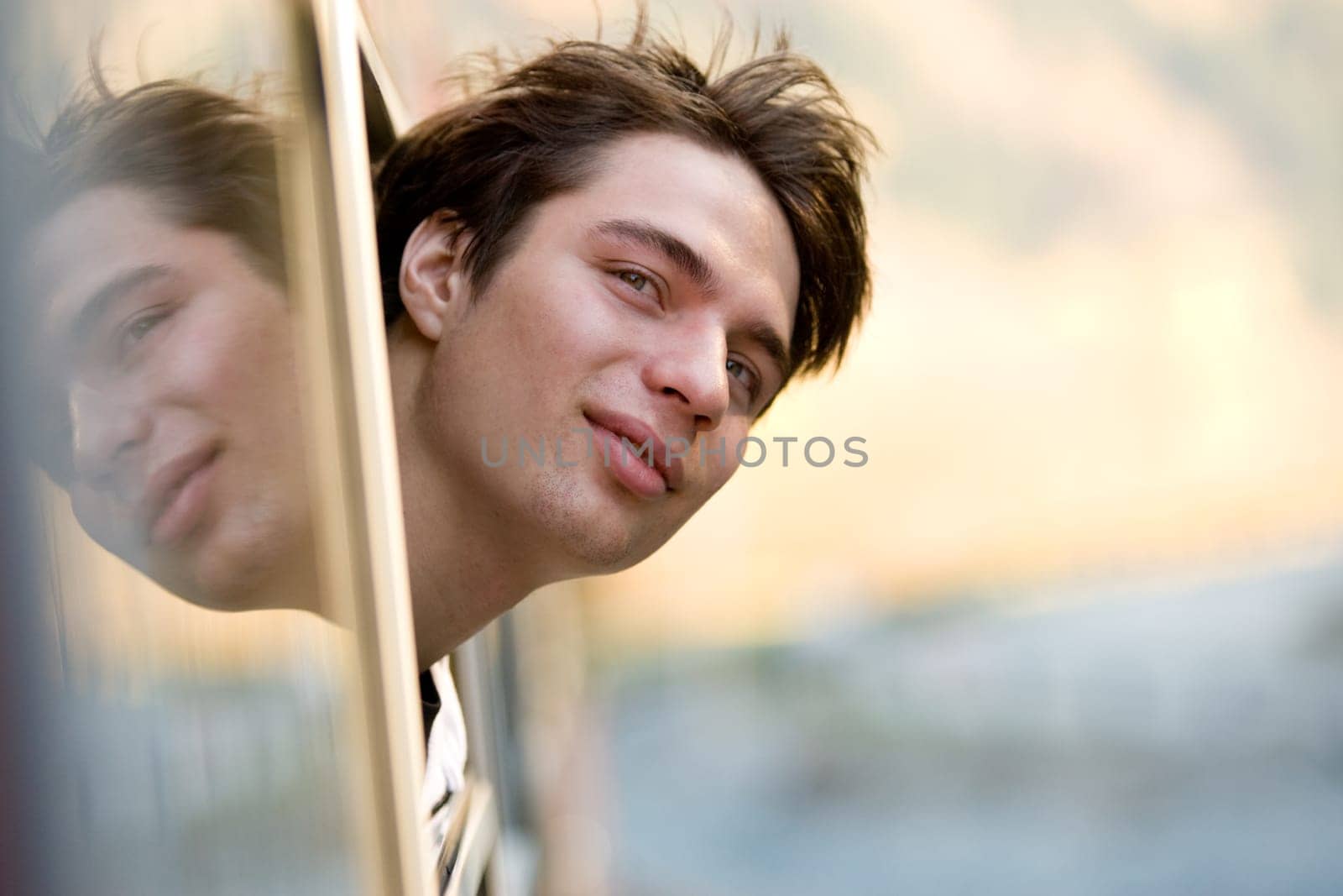 Photo of happy guy looking out of train window while commuting