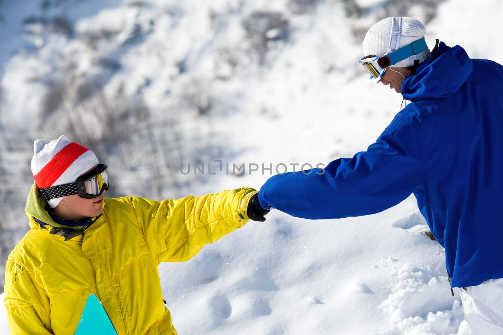 Portrait of two guys with snowboards climbing down snow-covered mountain