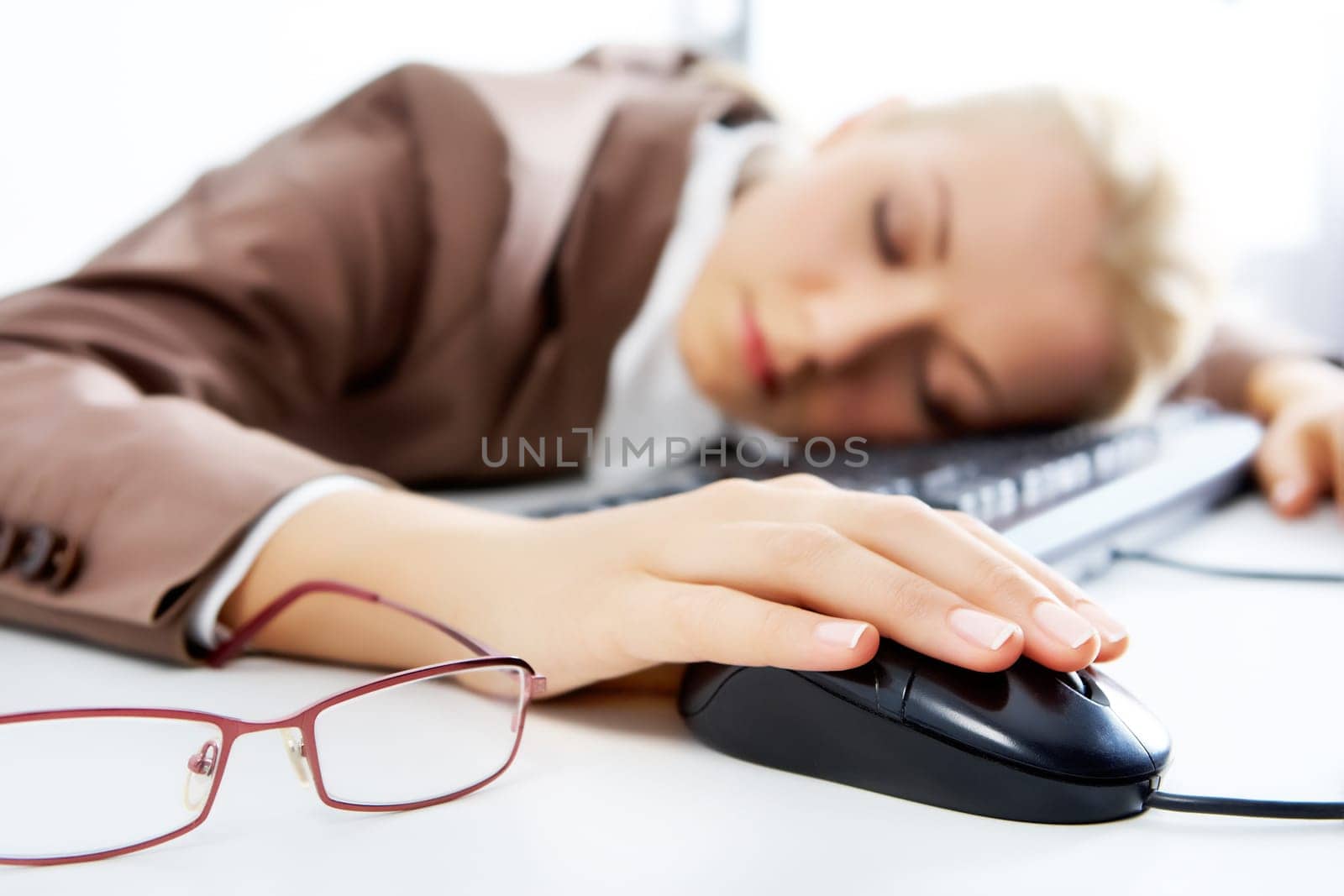 A young businesswoman sleeping on keyboard with a computer mouse