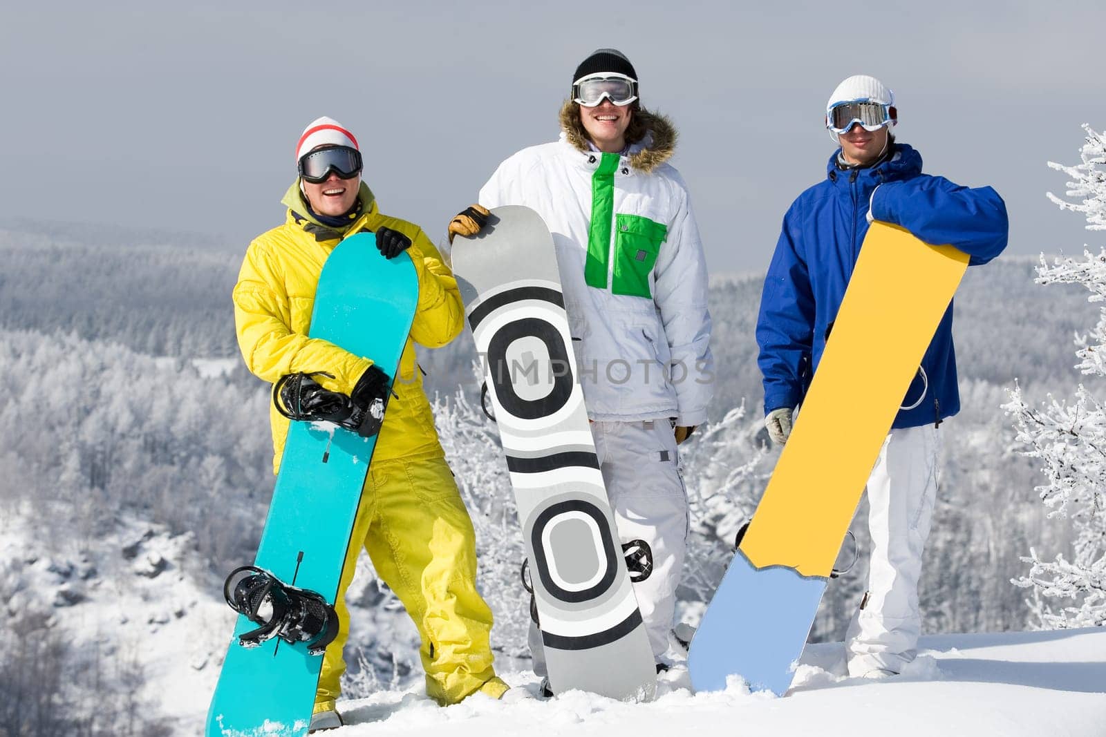 Portrait of three happy young men with snowboards looking at camera