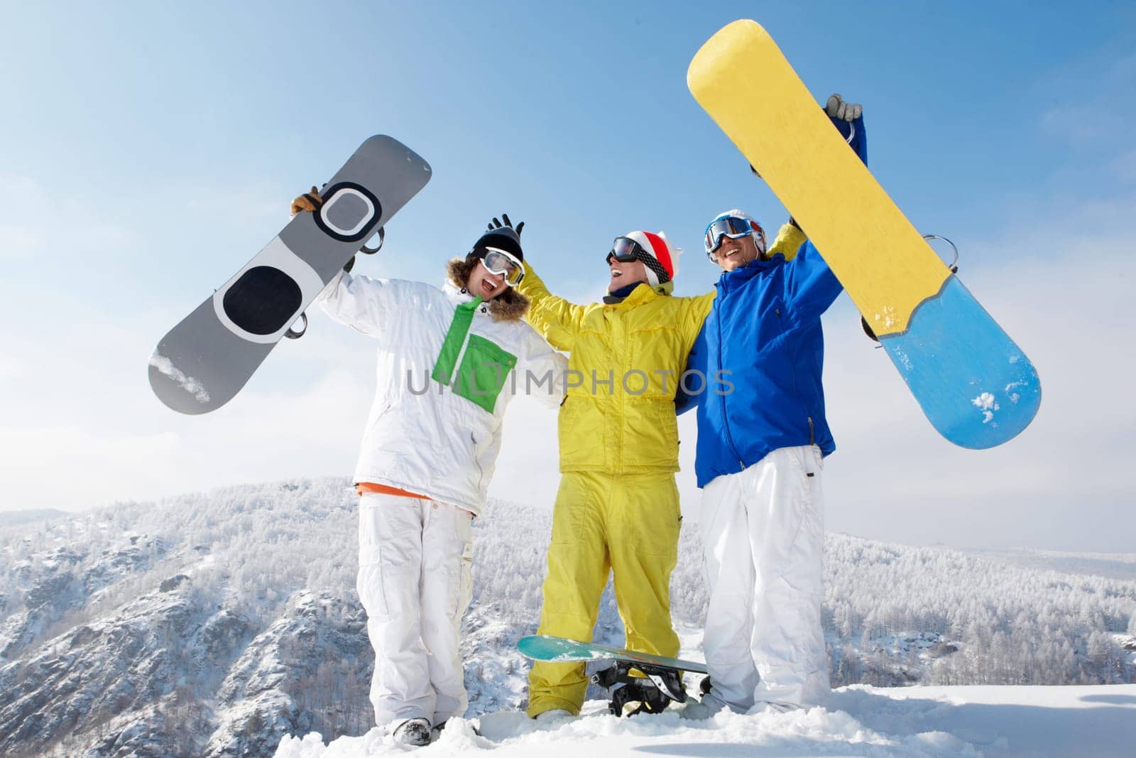 Portrait of happy three sportsmen raising their snowboards