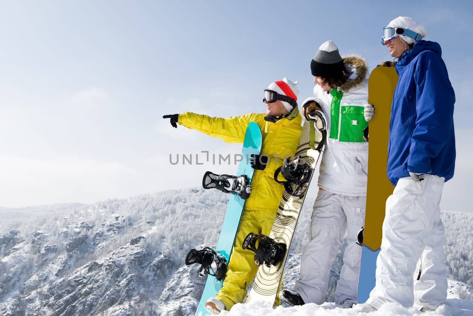 Portrait of three young men with snowboards interacting on top of mount