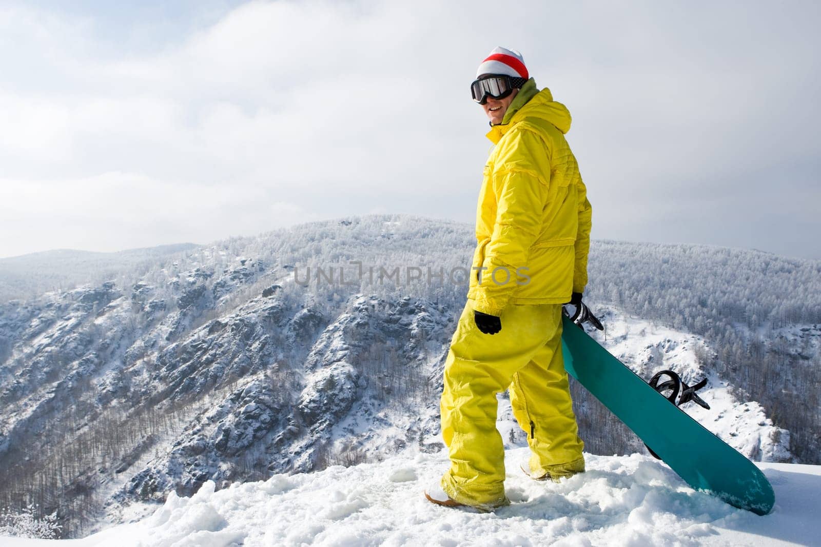 Portrait of young snowboarder smiling at camera on mountain top