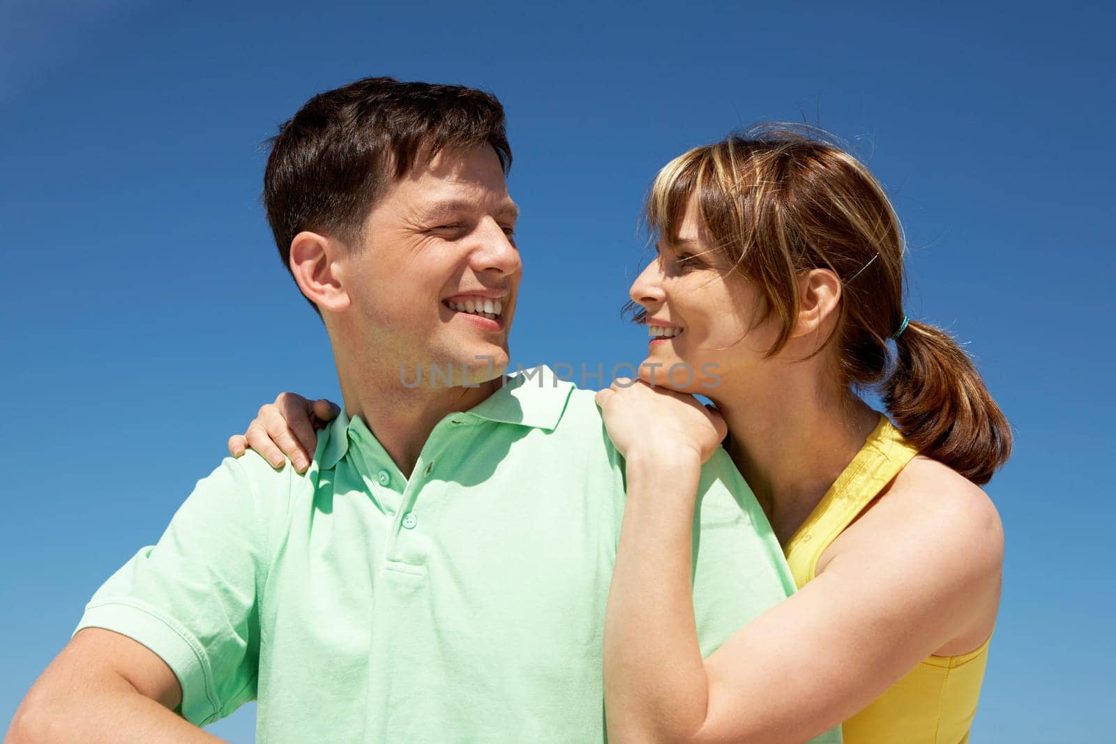 Photo of amorous couple smiling at each other while happy woman embracing her husband