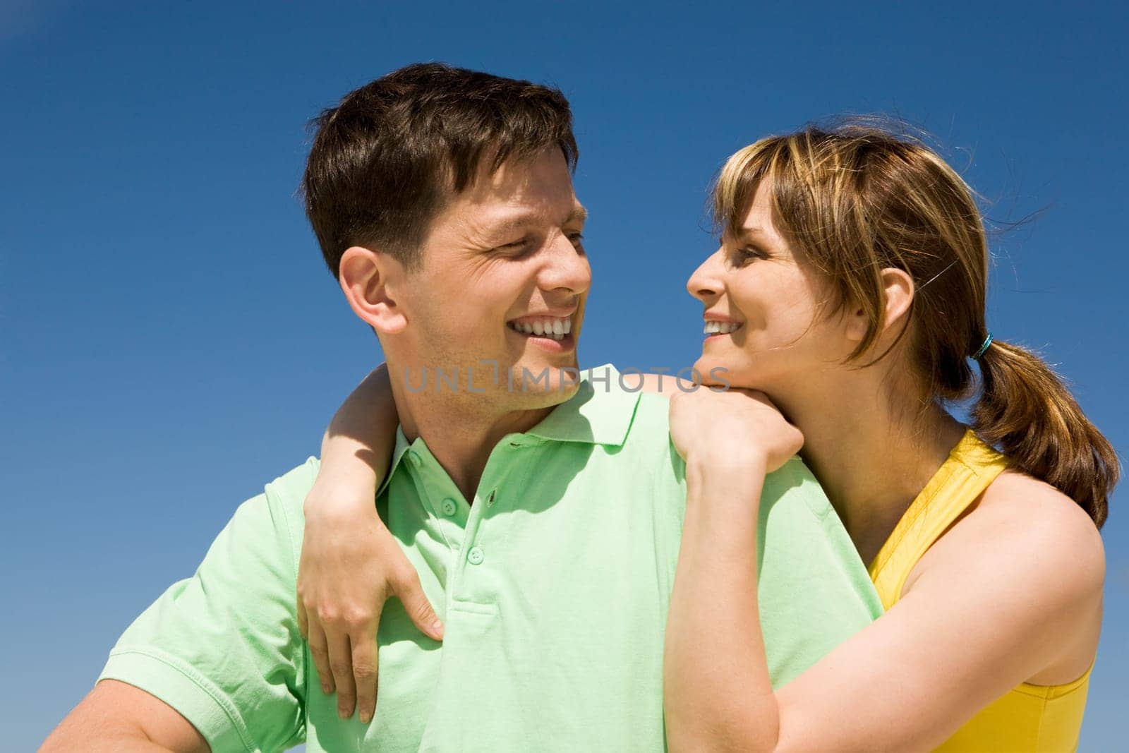 Photo of amorous couple smiling at each other while happy woman embracing her husband