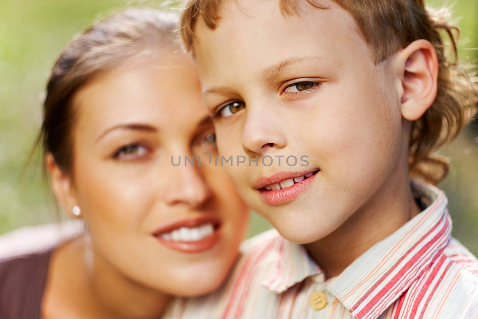 Portrait of handsome boy smiling at camera with his mother on background