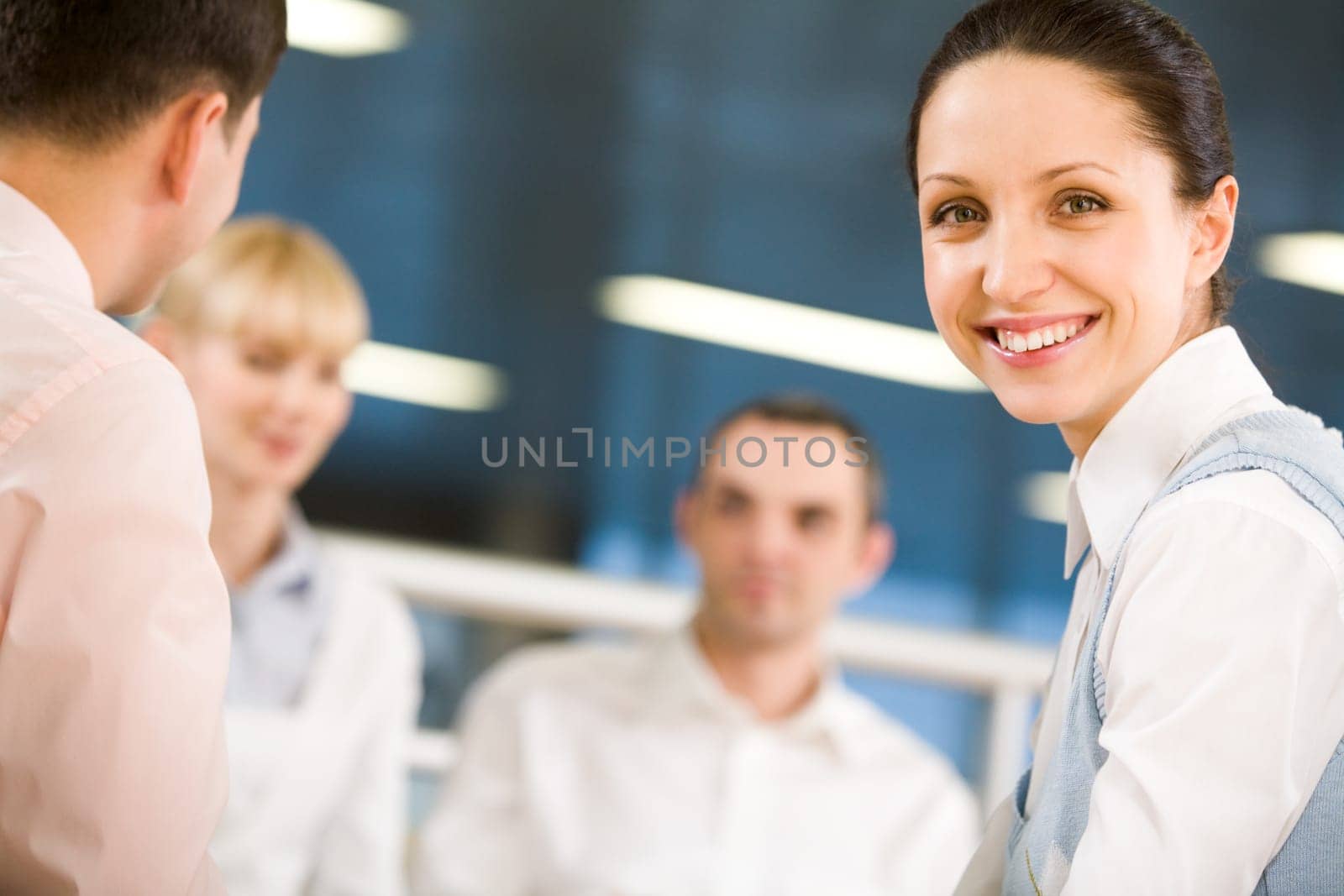Portrait of happy businesswoman smiling at camera on background of working employees