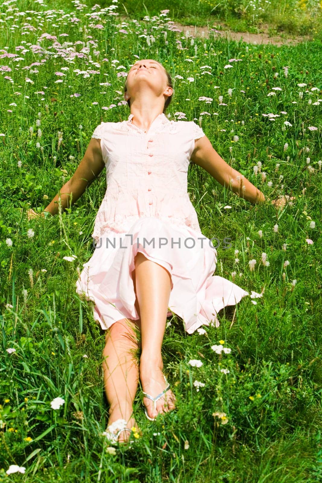 Photo of young girl lying on green grass and enjoying summer day with closed eyes