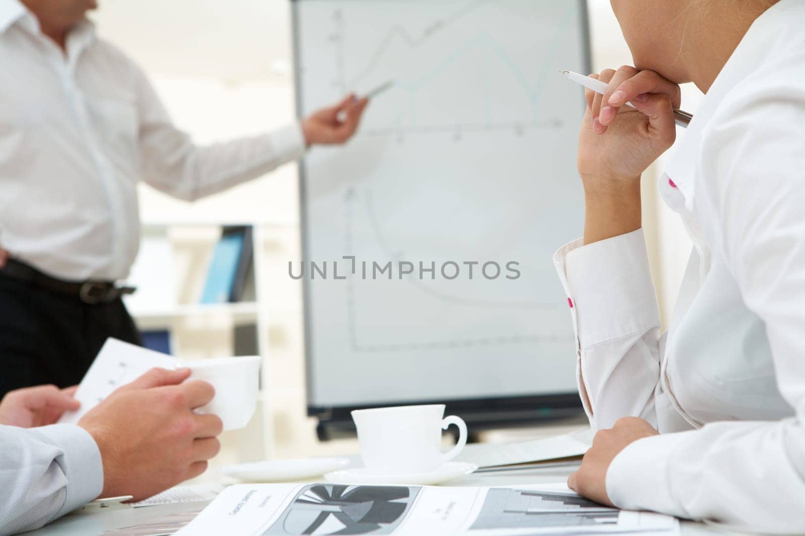 Photo of human hands over workplace on background of teacher by the whiteboard