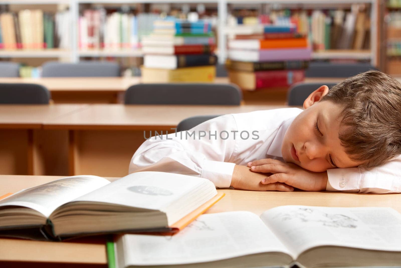 Image of young boy sleeping near books in the library