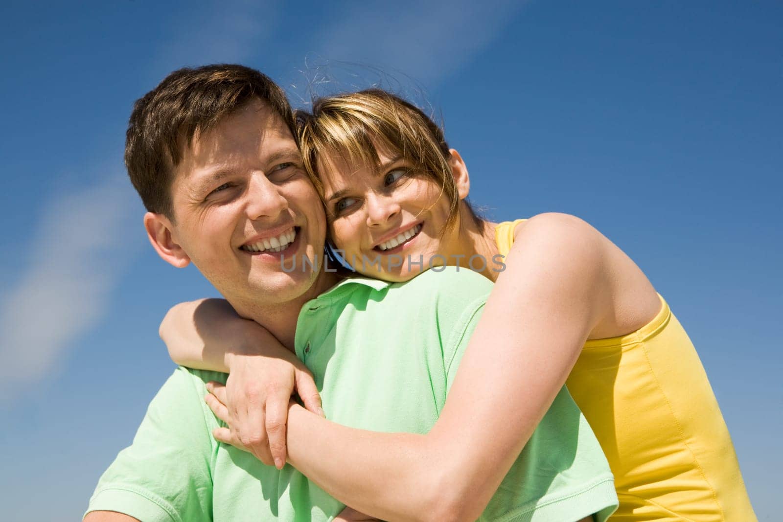 Photo of pretty female embracing happy man against bright blue sky