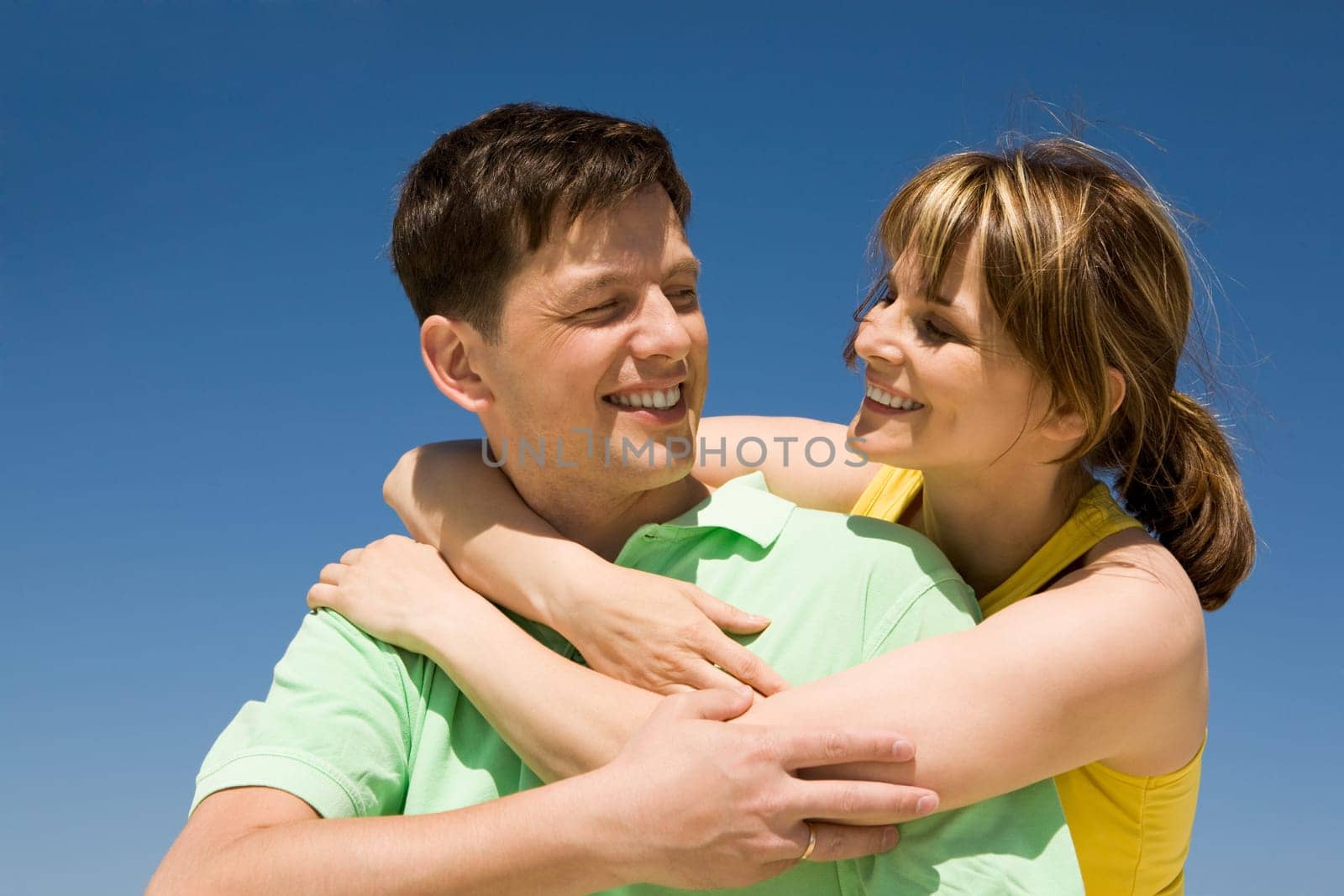 Photo of happy woman embracing her husband against bright blue sky
