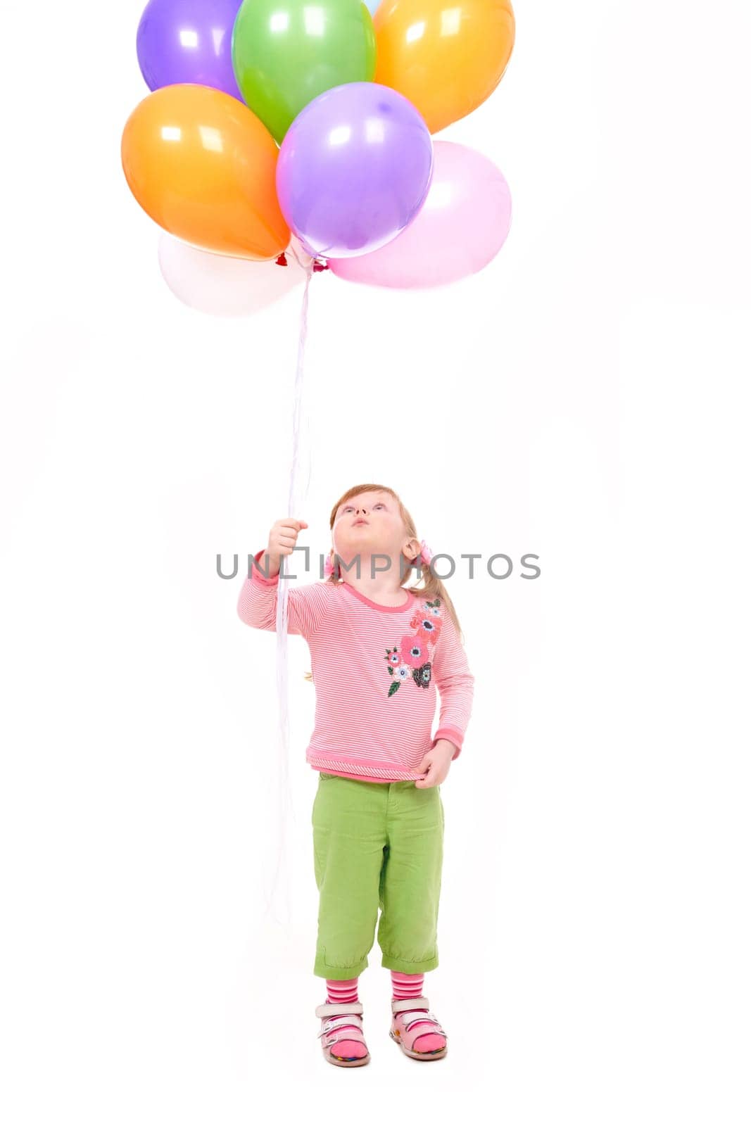 Image of small girl with helium balloons looking upwards at them