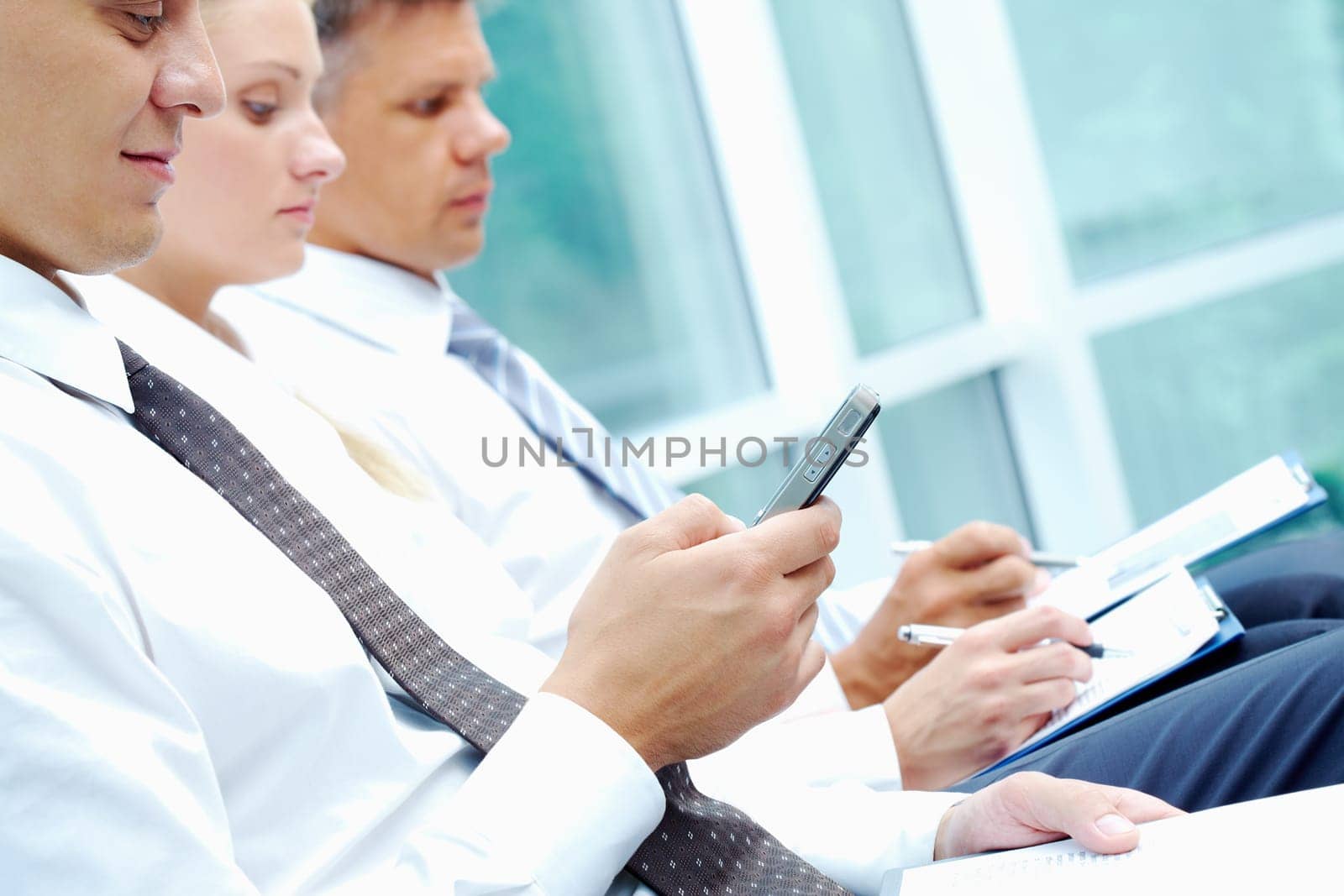 Image of businessman writing sms at conference with working partners on background