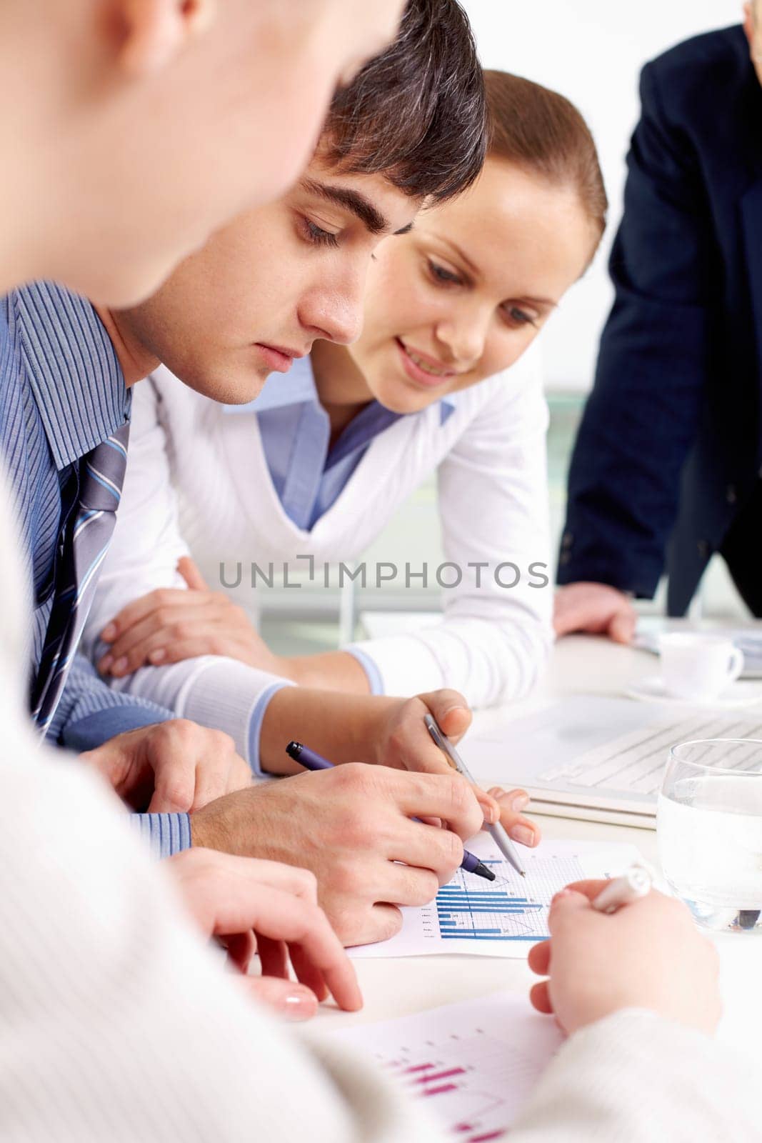 Portrait of confident man looking at document being discussed by co-workers