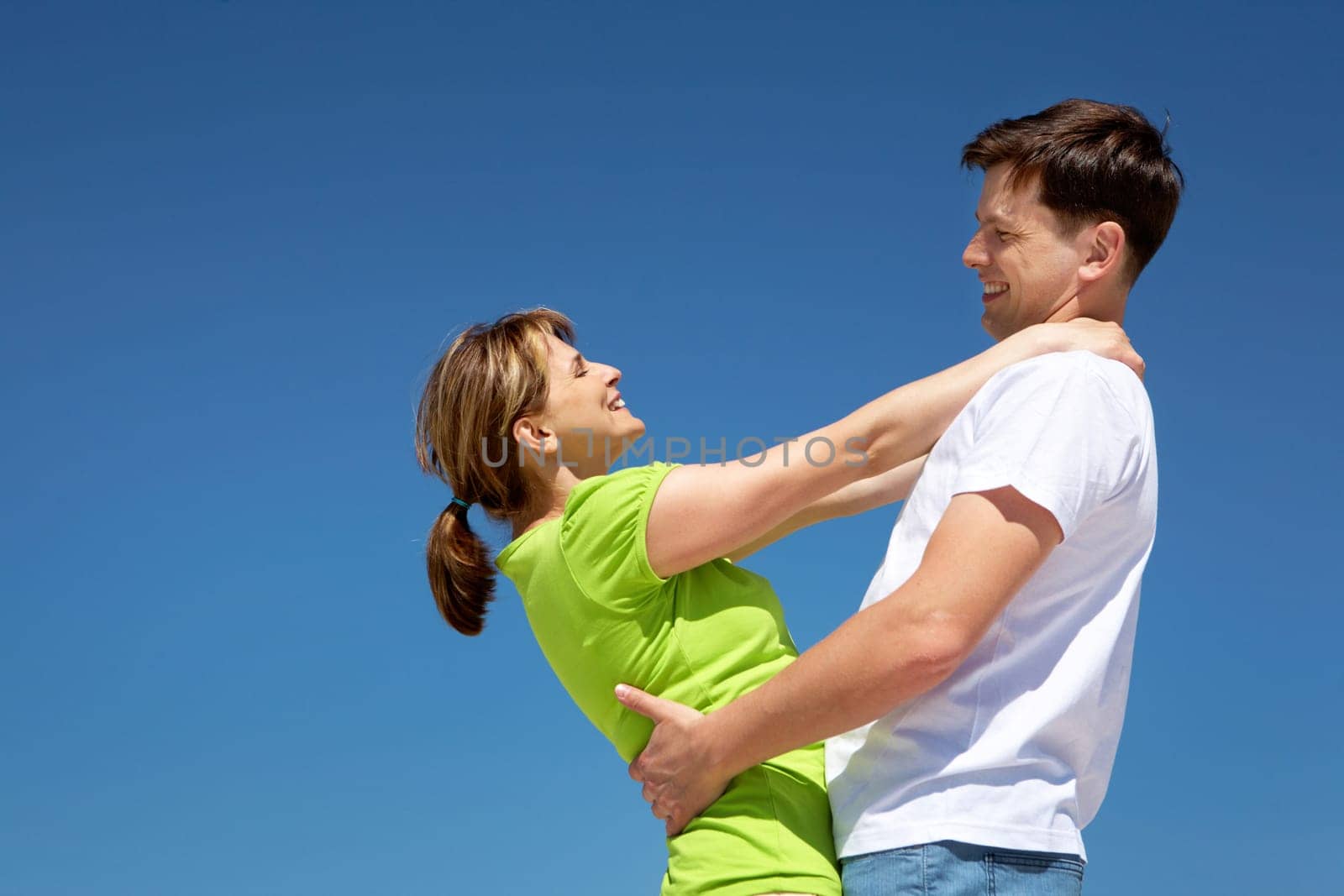 Photo of happy couple embracing against blue sky