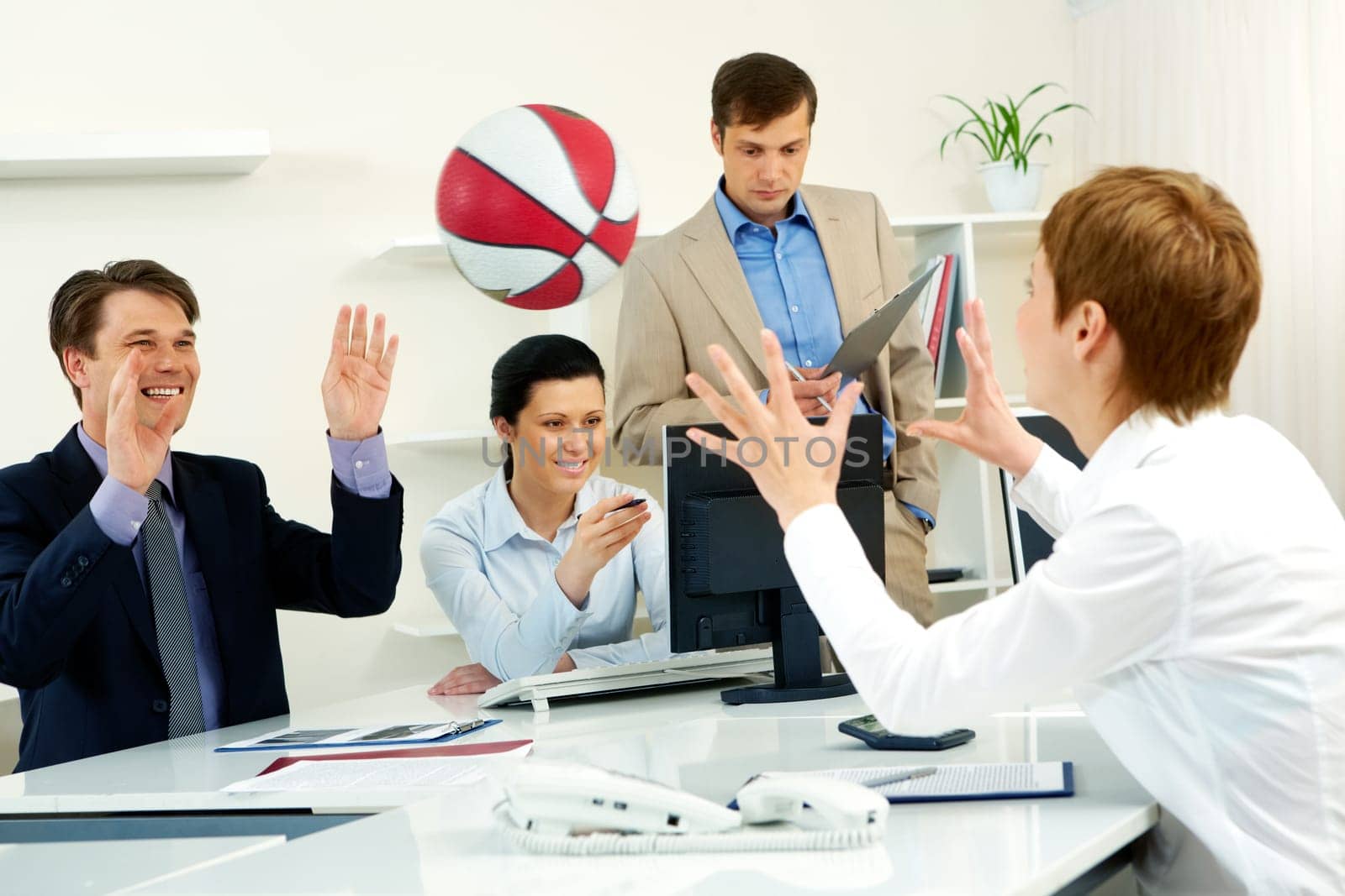 Businesspeople throwing basketball in the office