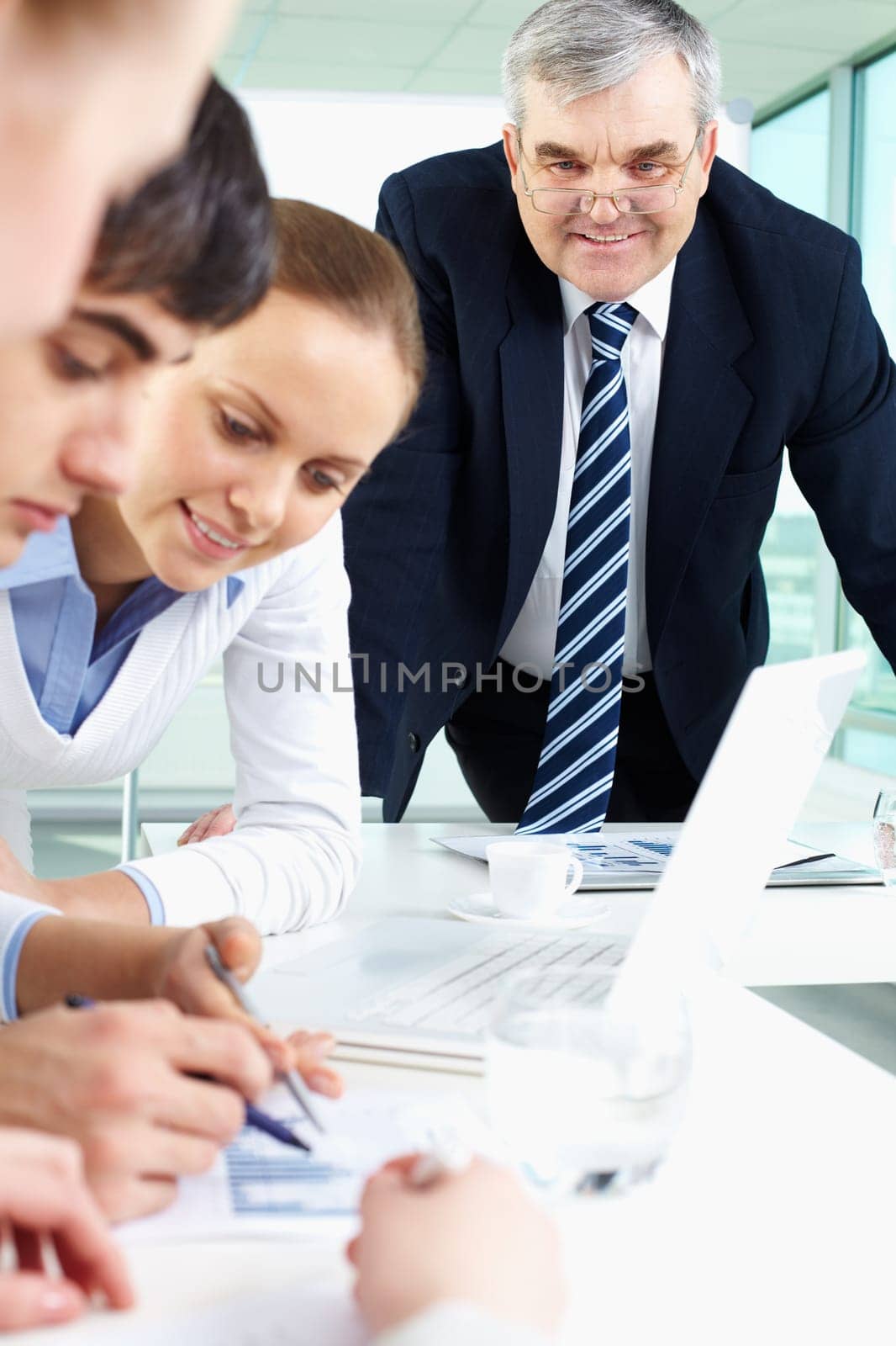 Portrait of confident man looking at document being discussed by co-workers