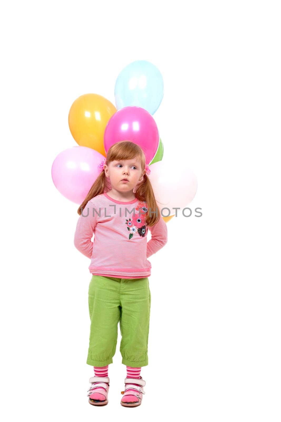 Image of small girl with helium balloons looking aside at party
