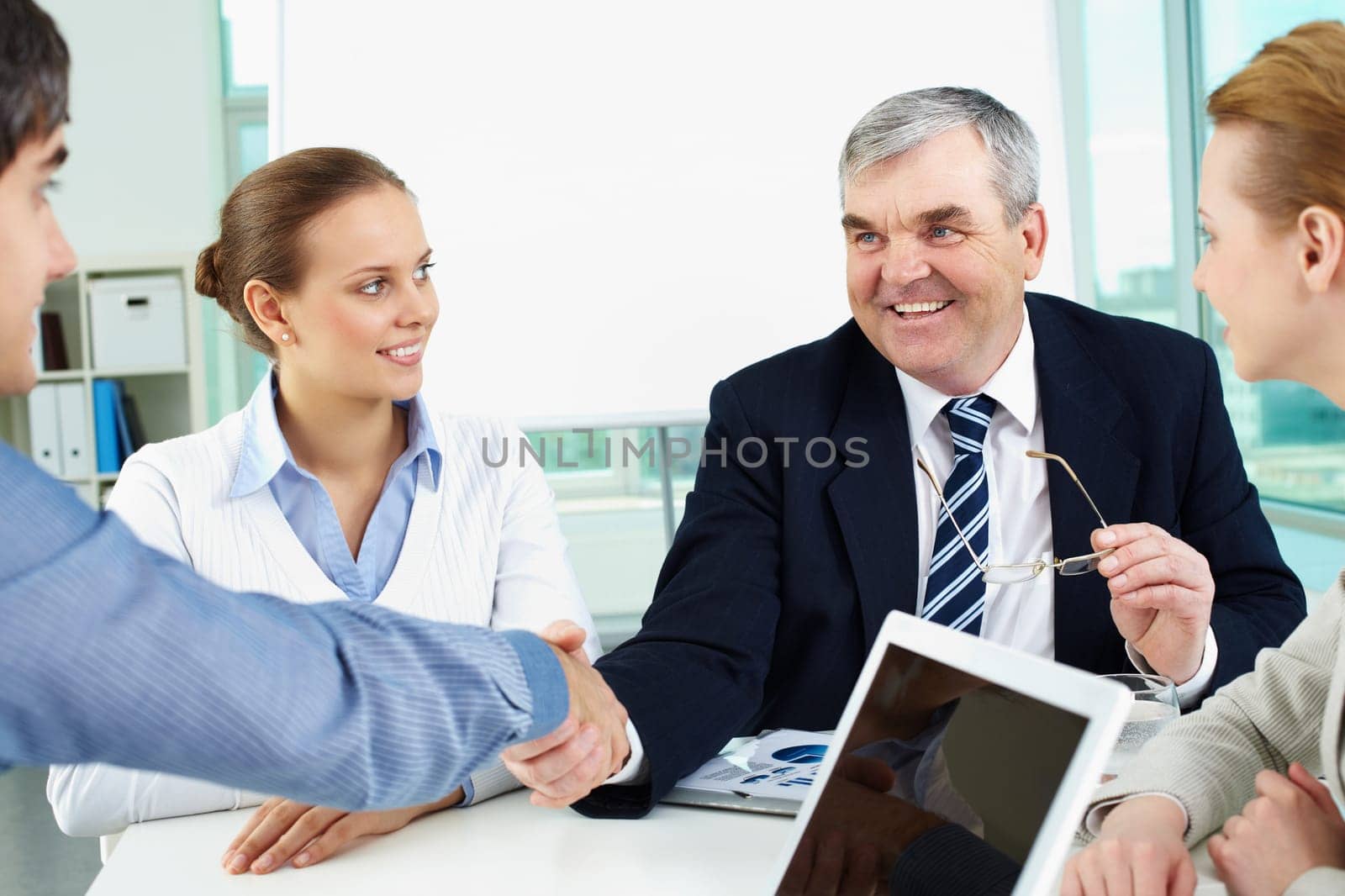 Photo of successful businessmen handshaking after striking deal with partners near by