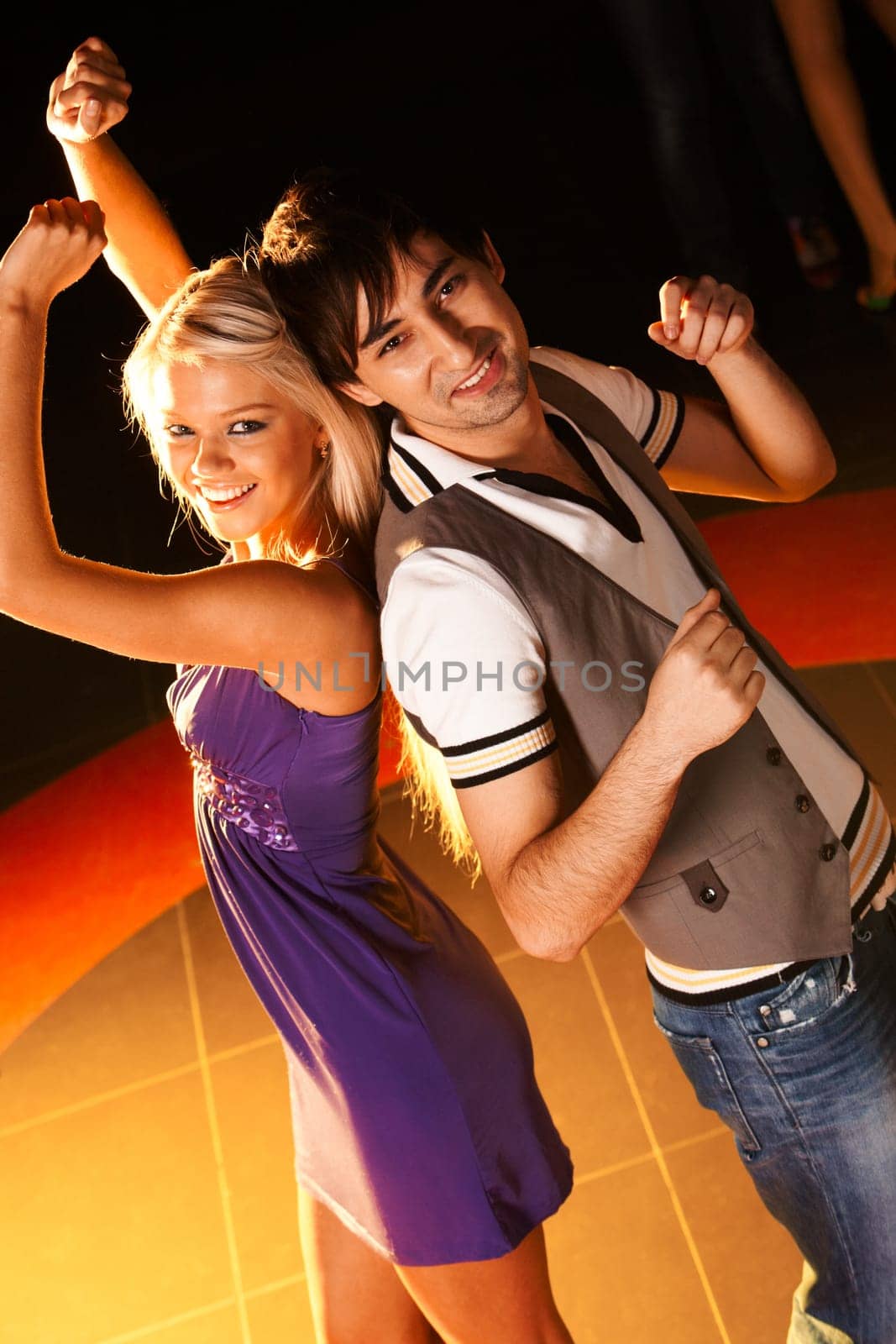 Positive couple dancing at disco and looking at camera