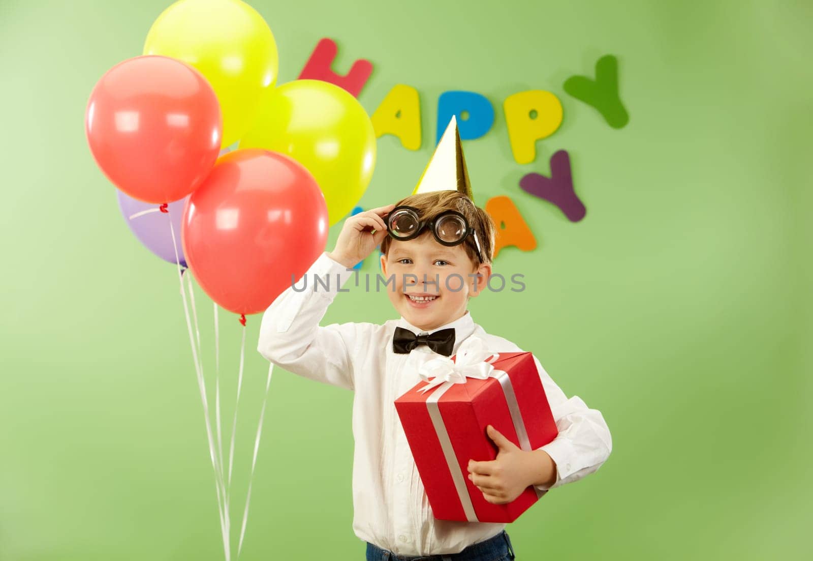 Portrait of happy lad with giftbox putting off funny eyeglasses on birthday party