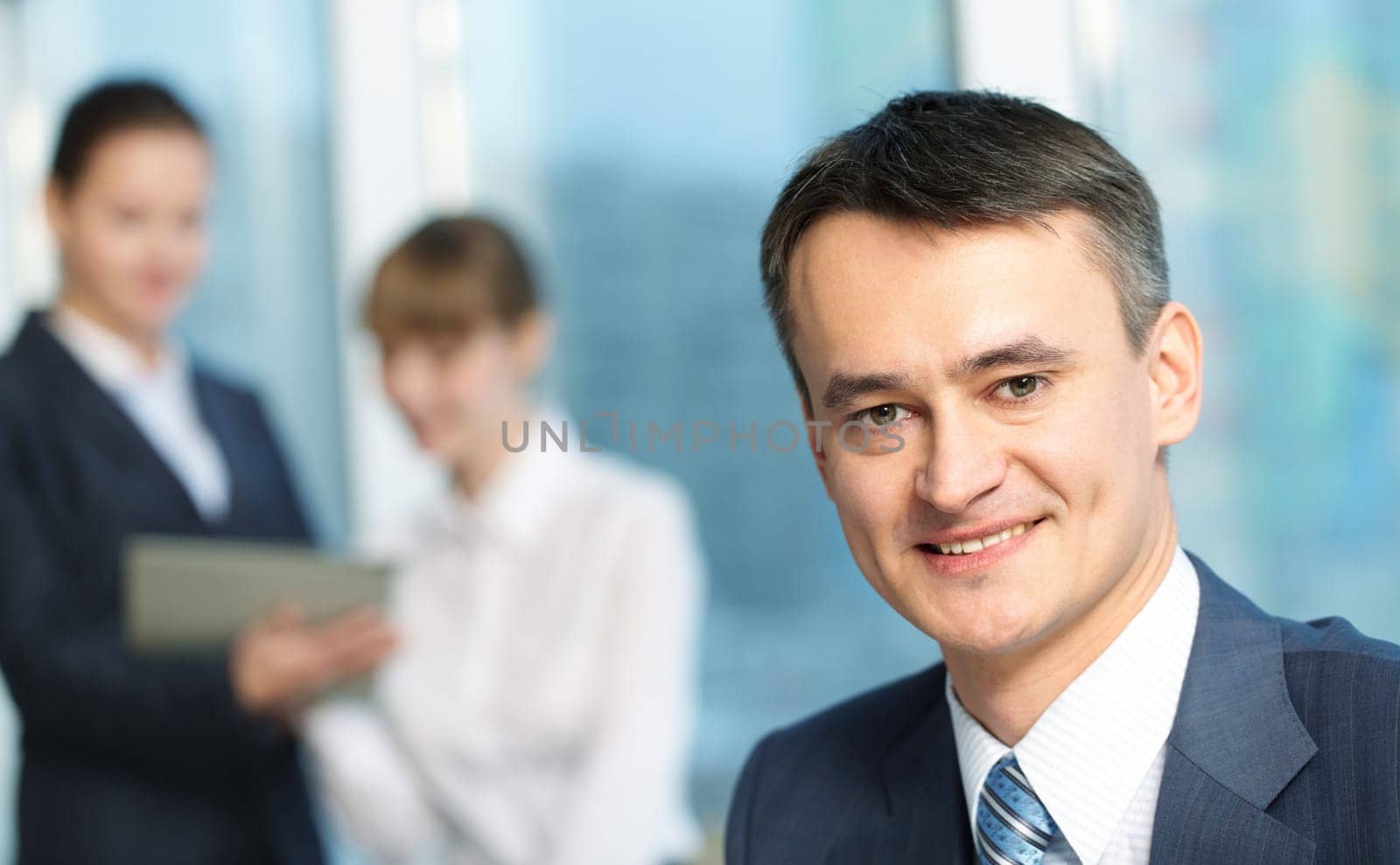 Portrait of a mature smiling manager against his colleagues