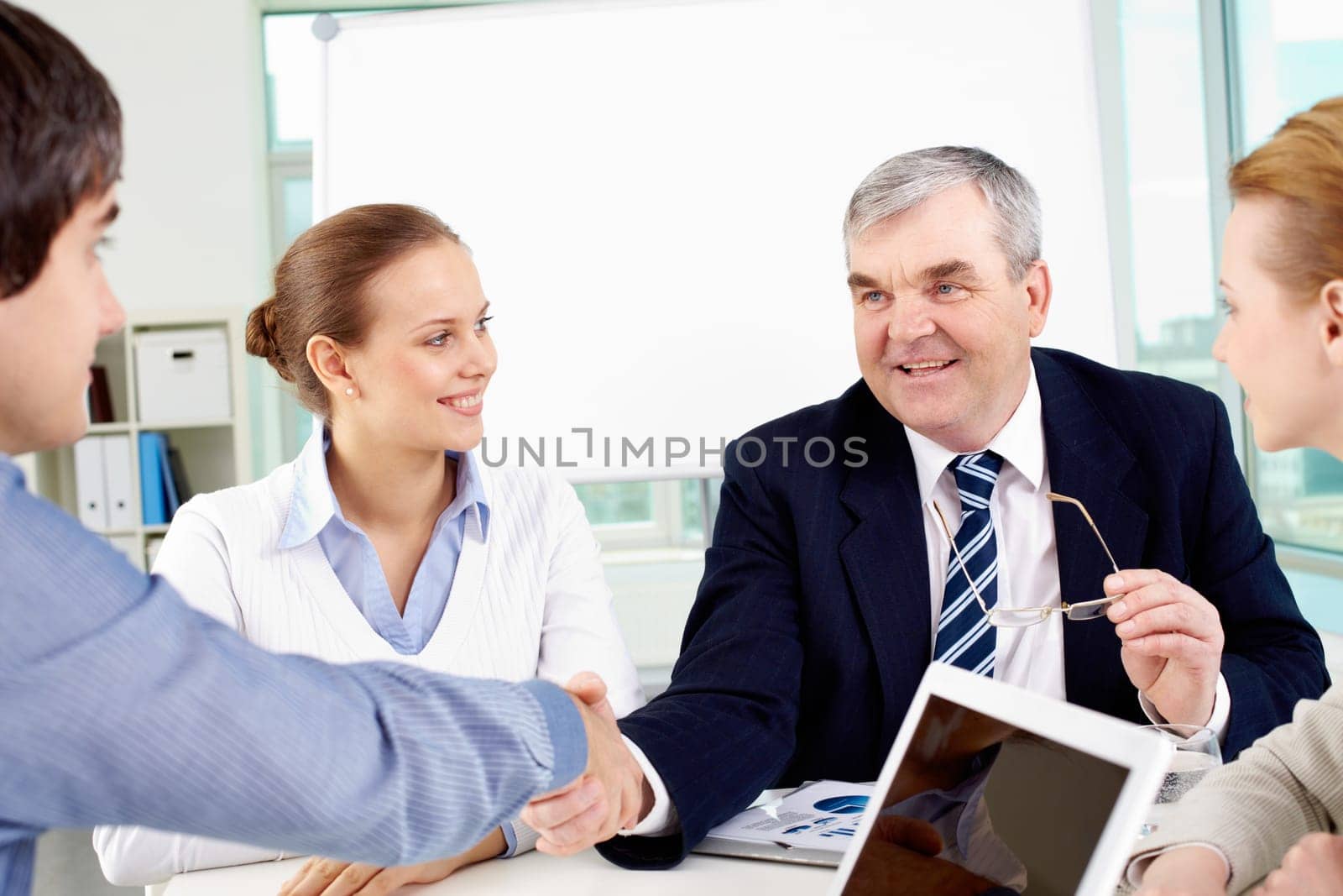 Photo of successful businessmen handshaking after striking deal with partners near by