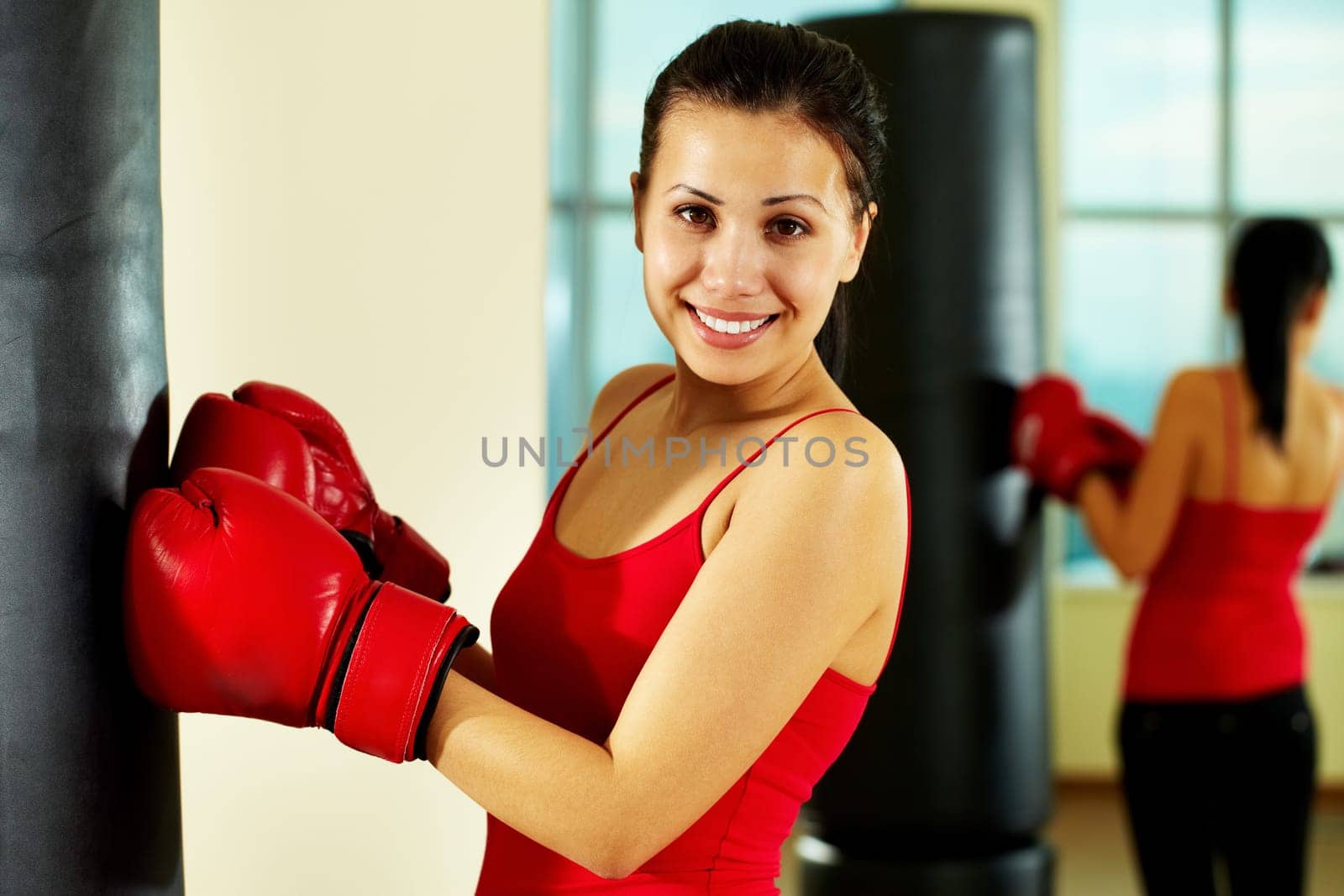 Portrait of young woman in red boxing gloves looking at camera