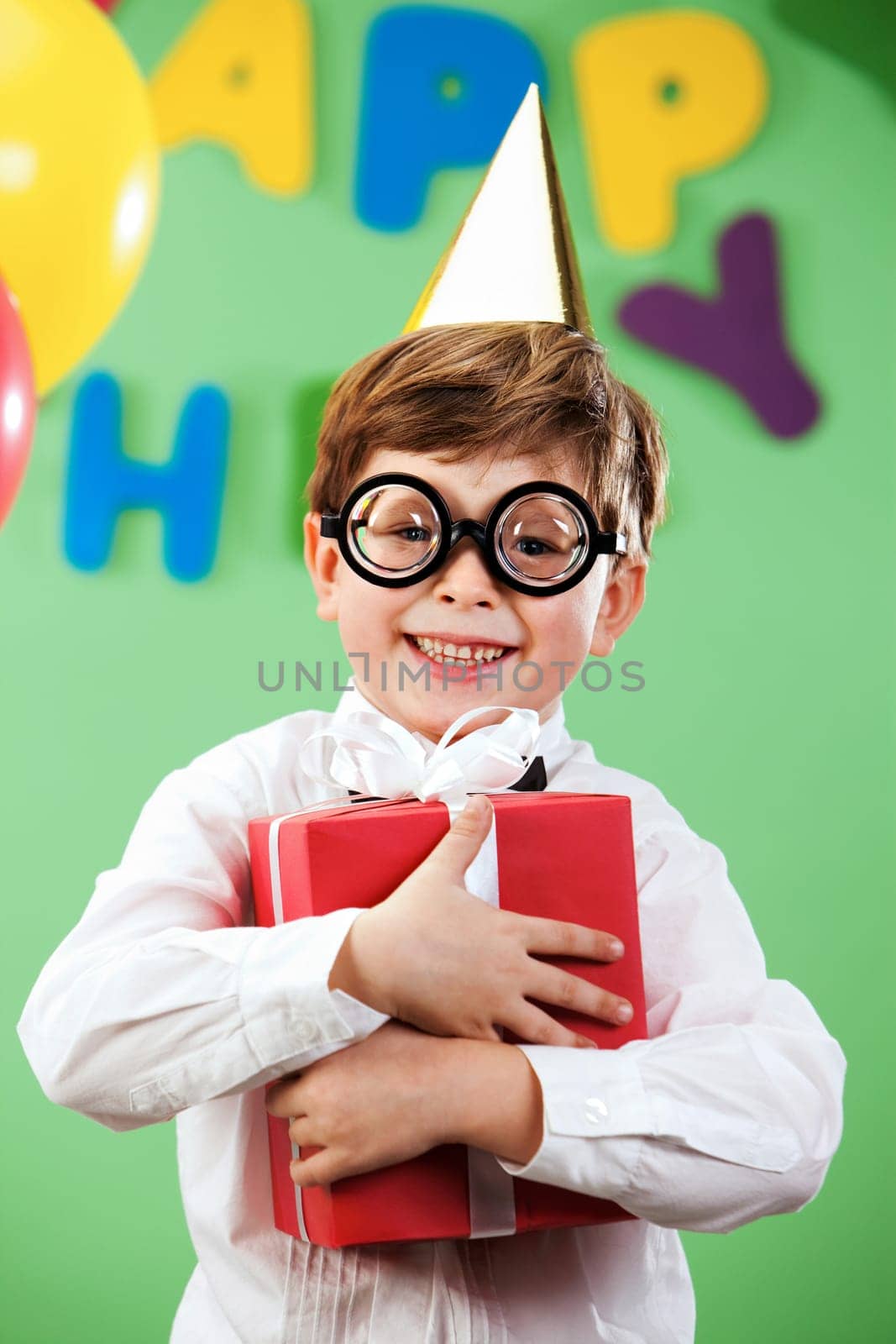 Portrait of happy lad in funny eyeglasses on birthday party with present