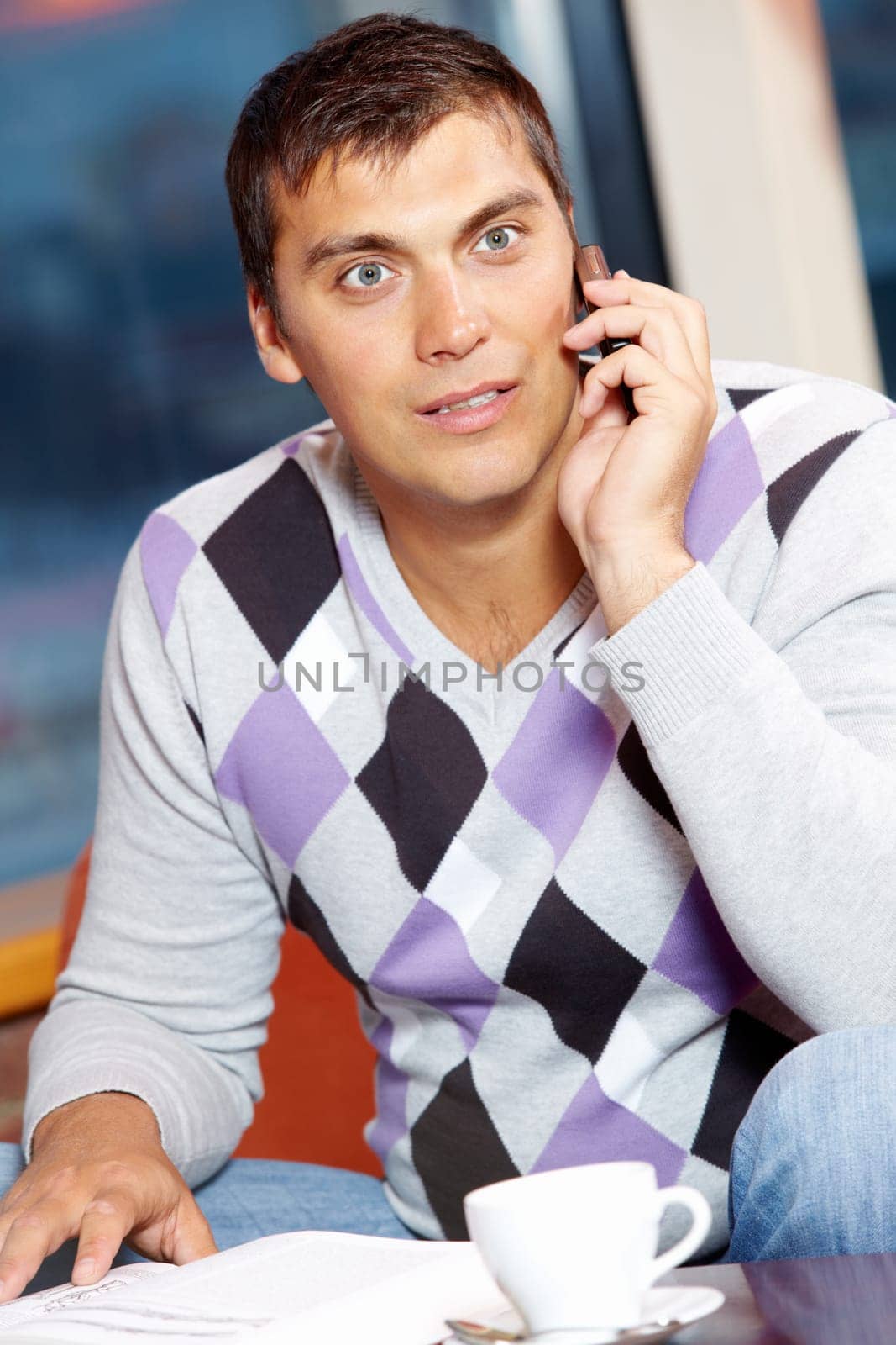 Portrait of handsome man speaking by cellular phone in cafe