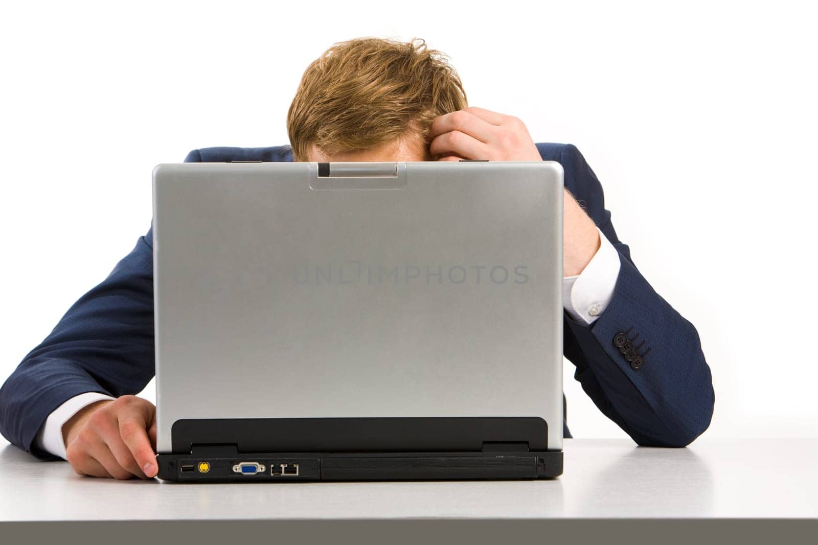 Portrait of tired businessman touching his head while sitting in front of laptop