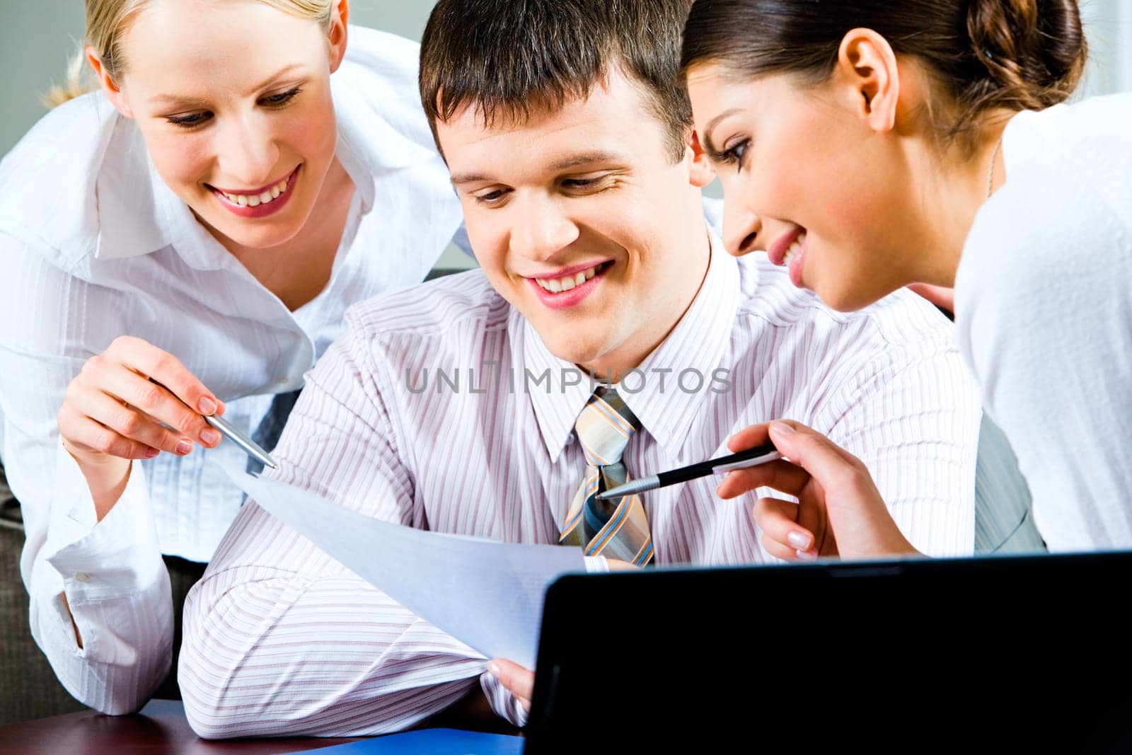 Portrait of a businessman looking at document with smile with two beautiful smiling business ladies near by