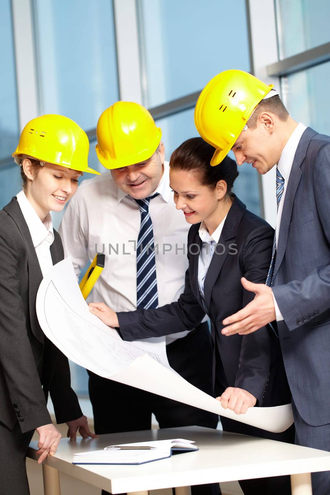 Four engineers standing at table and discussing a project